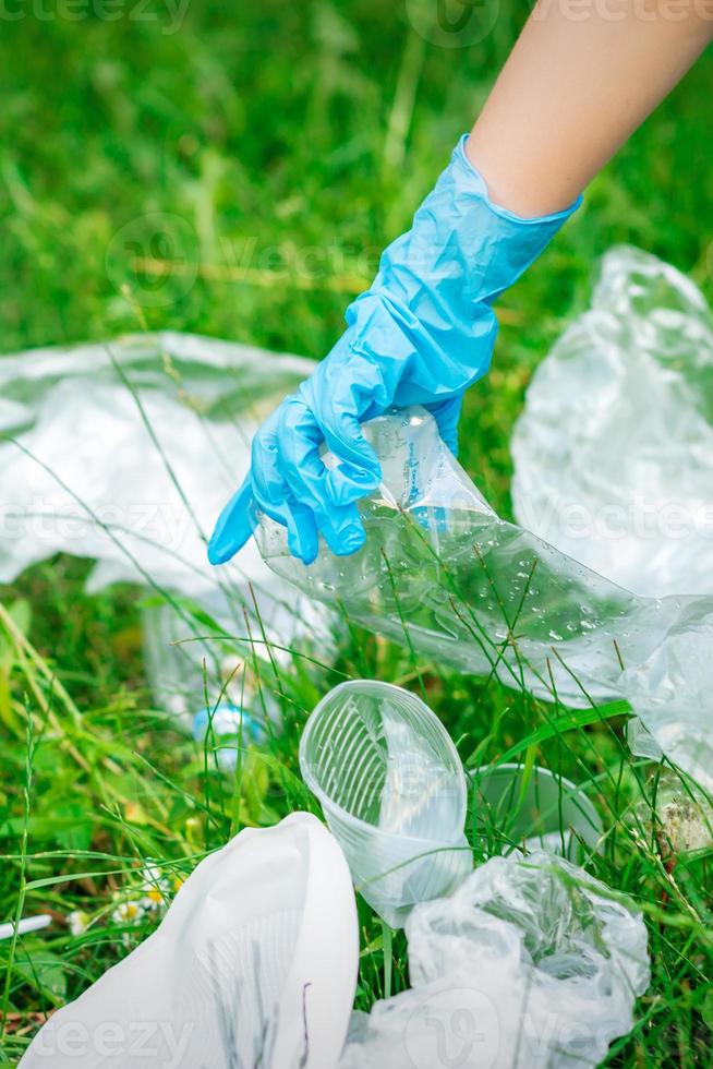 Hand of child cleans the park from plastic debris photo