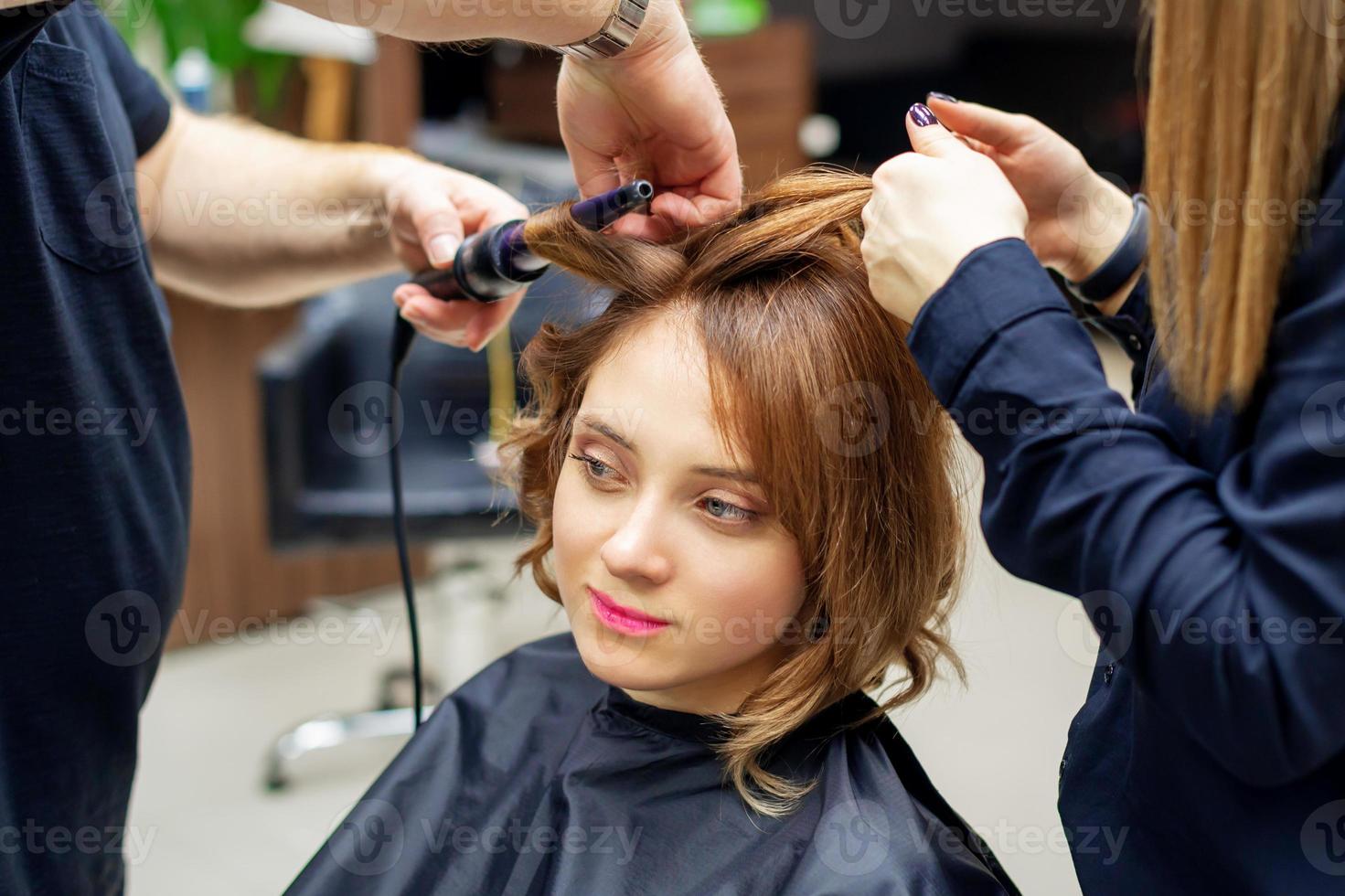 Hairdresser curling long light brown hair photo