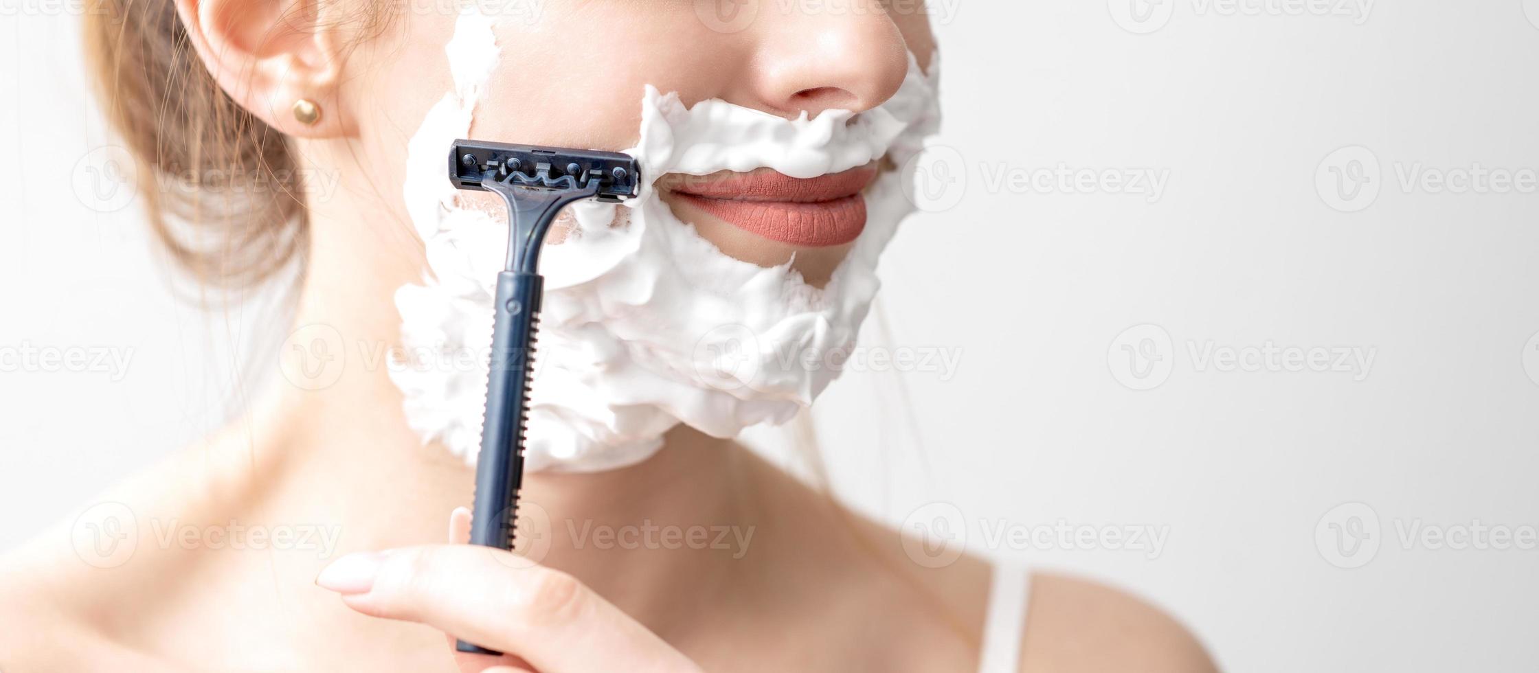 Woman shaving her face by razor photo