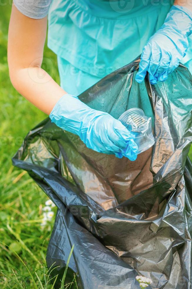 Child picks plastic trash from grass photo
