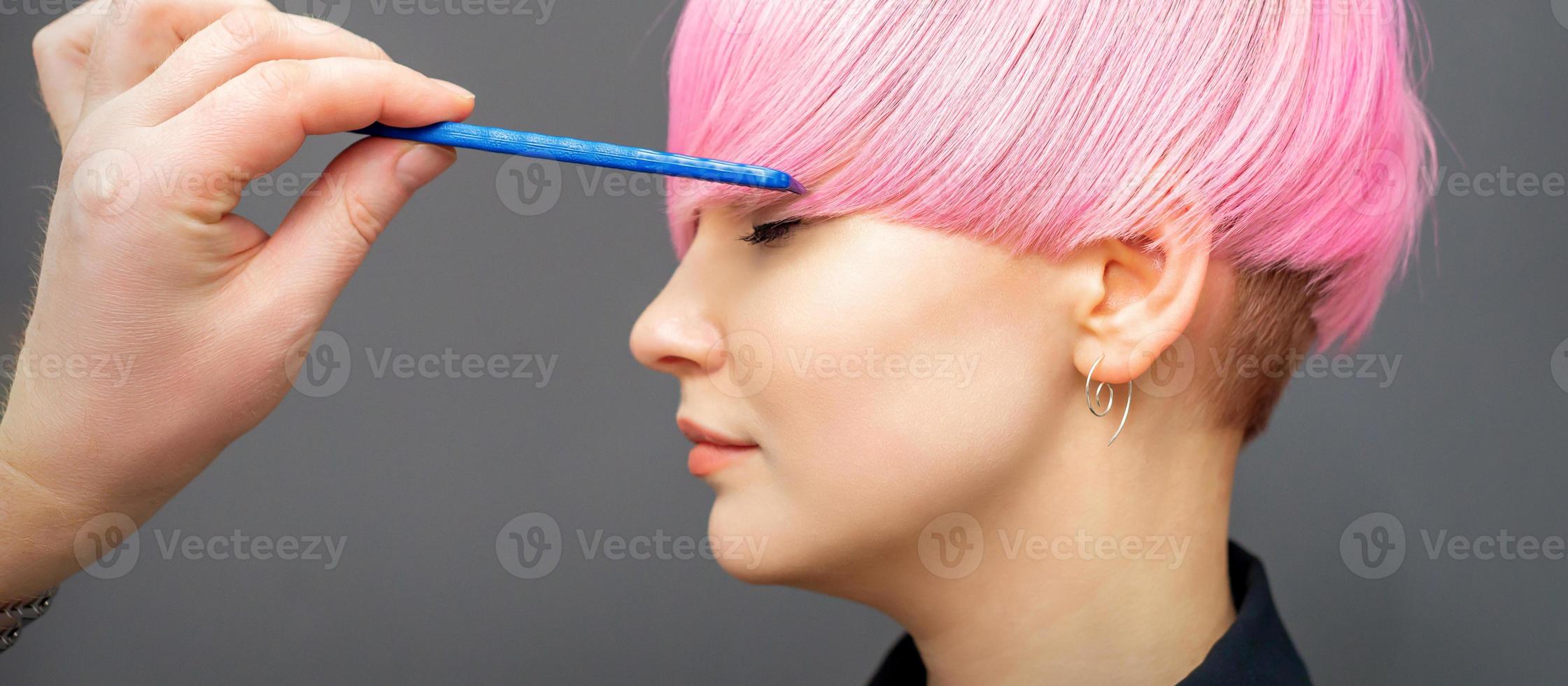 Hairdresser checking woman's pink hairstyle. photo