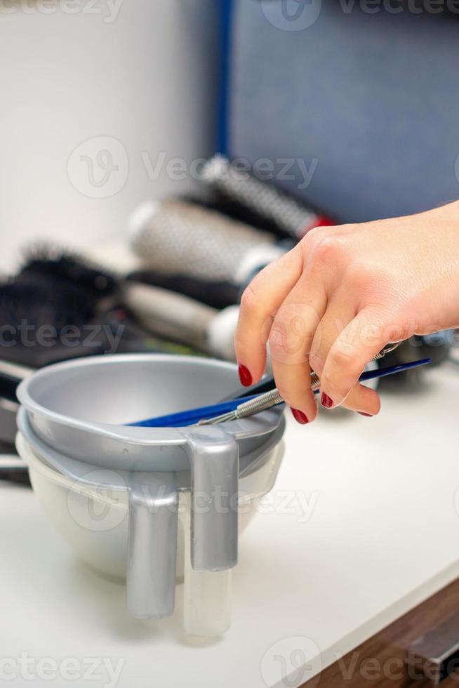 Hand of hairstylist prepares dye in bowl photo