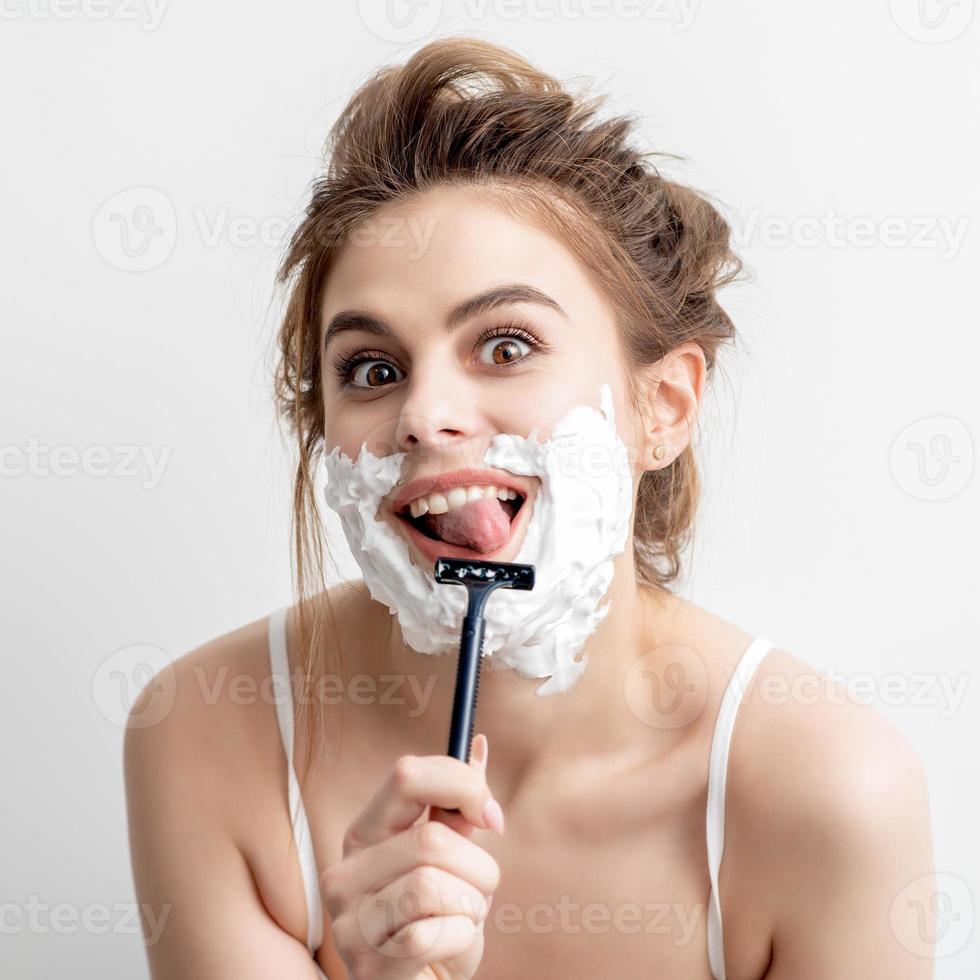 Woman shaving her face by razor photo