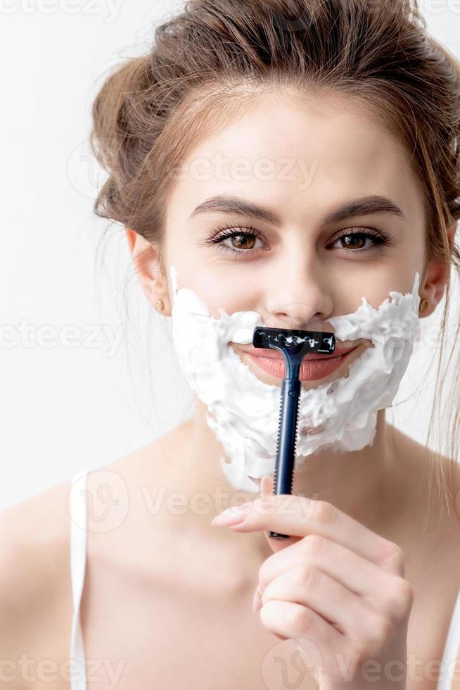 Woman shaving her face by razor photo