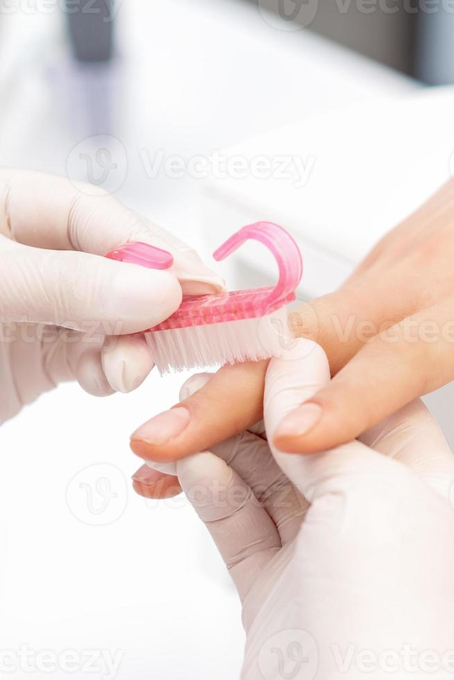 Manicure master uses brush to clean dust from nails photo