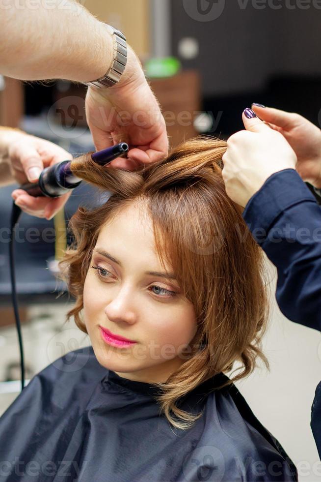 Hairdresser curling long light brown hair photo