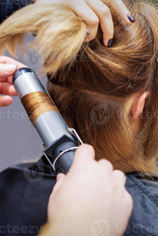 Hairdresser curling long light brown hair photo