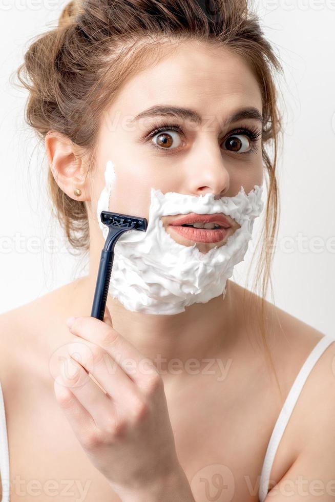 mujer afeitándose la cara con navaja foto