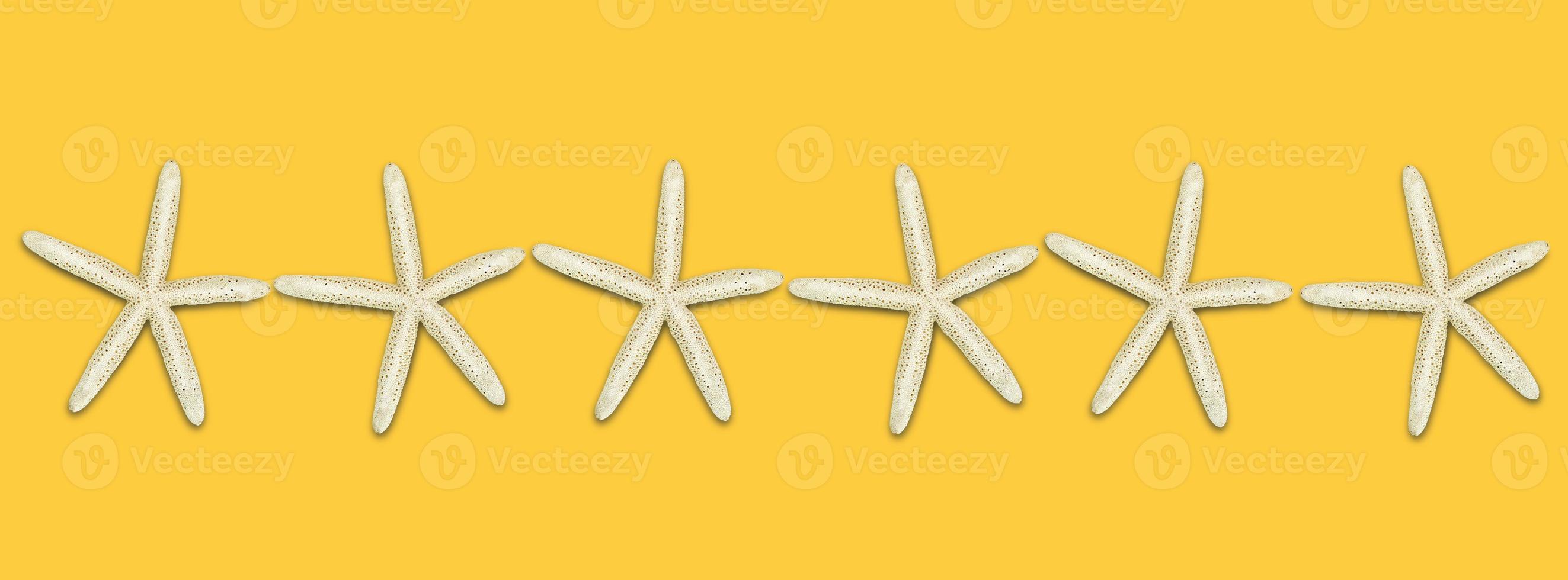 Starfish in a row in the middle on a yellow background. Banner. The idea of rest, beach, tourism. Copy space photo