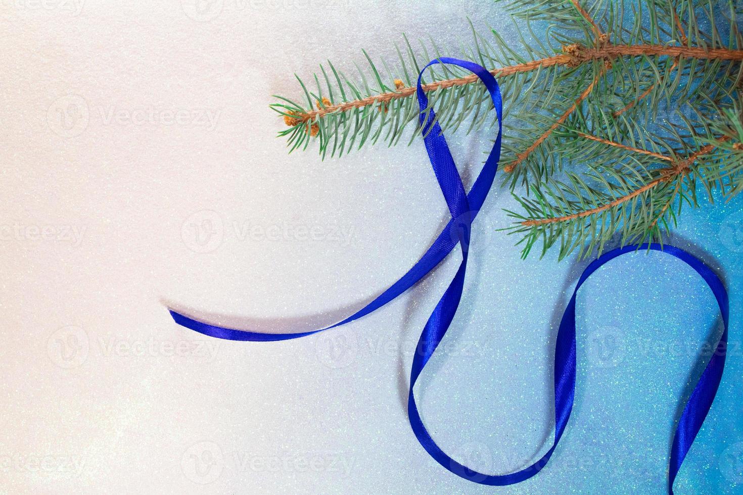 Spruce branch with blue satin ribbon on white-blue background. Christmas and New Year card photo