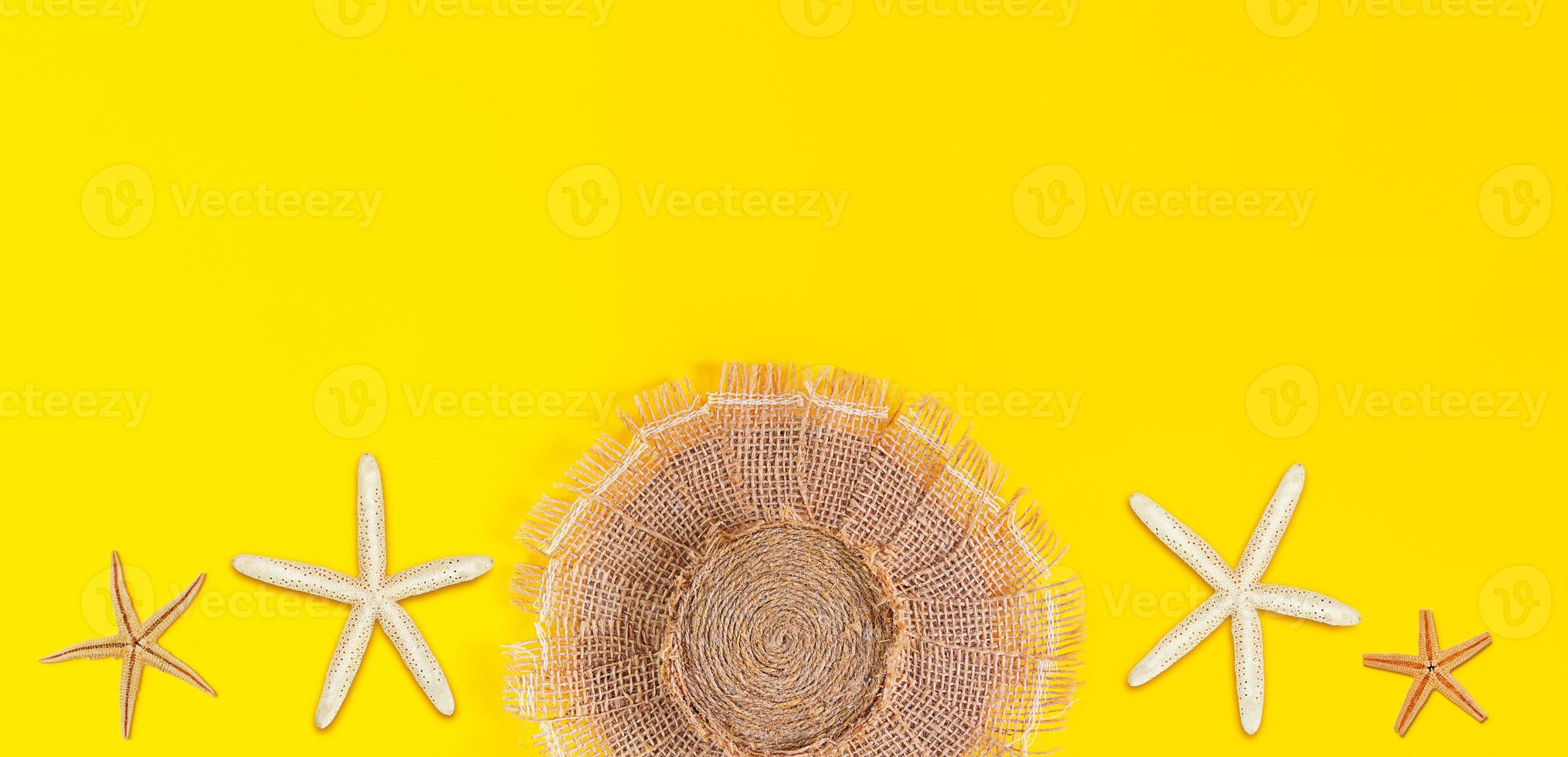 sombrero de playa hecho de arpillera con estrellas de mar blancas y marrones sobre fondo amarillo. bandera. concepto de verano, vacaciones. copie el espacio foto