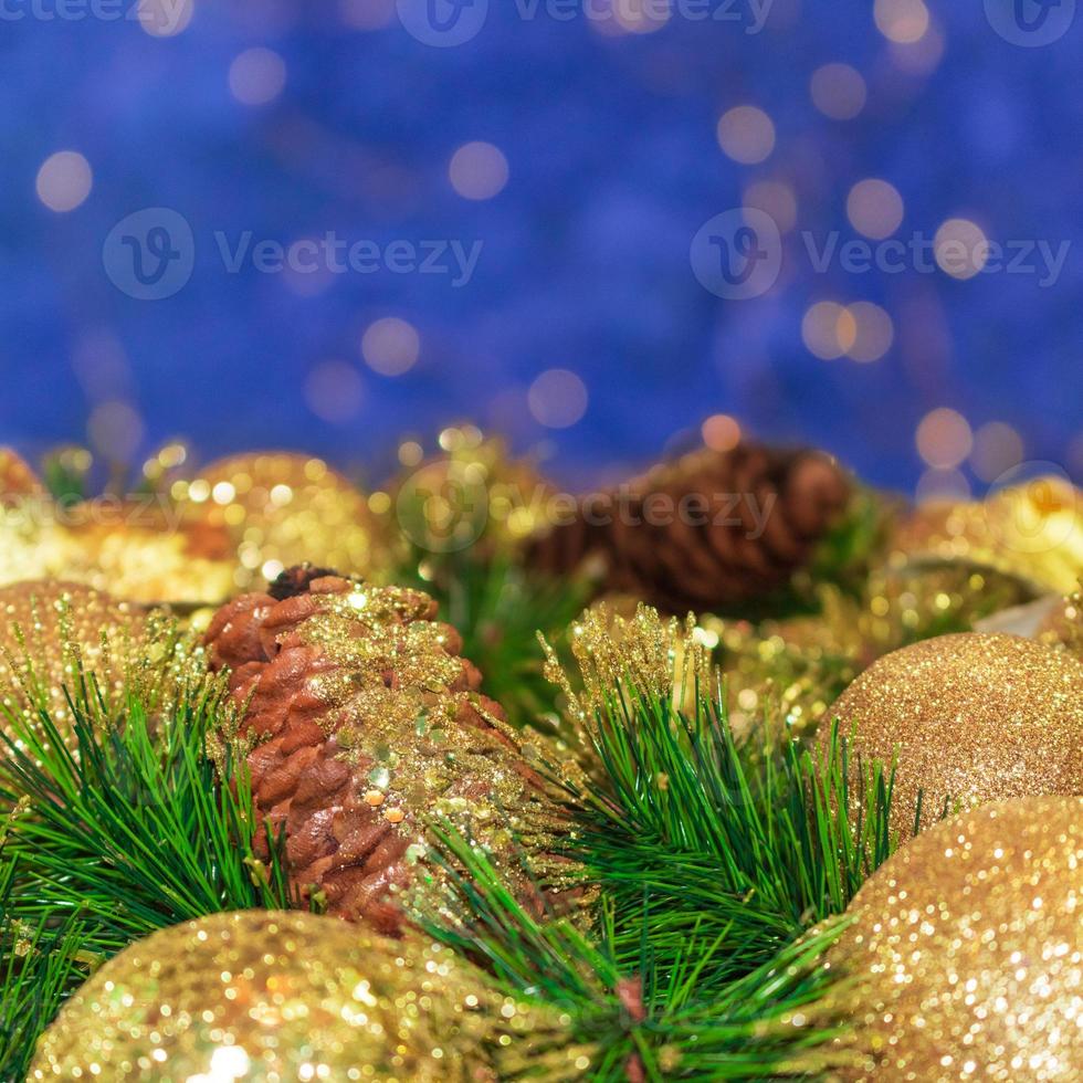 bolas de navidad amarillas brillantes y cono con cortezas y ramas de pino. fondo azul con bokeh. tarjeta de año nuevo. copie el espacio foto