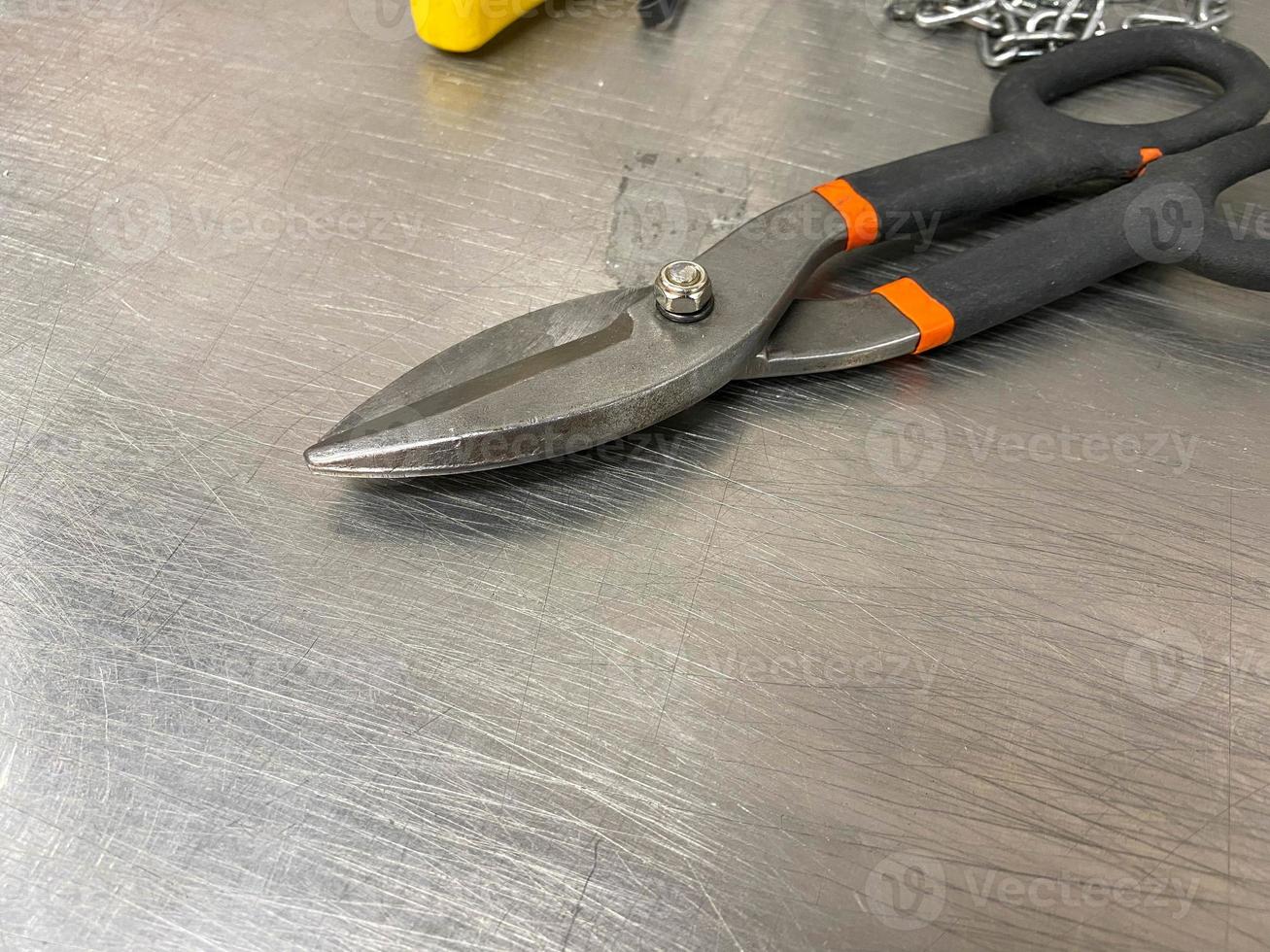 Large iron sharp metal scissors metal cutters lie on an iron table. Hand-held locksmith tools. The background photo
