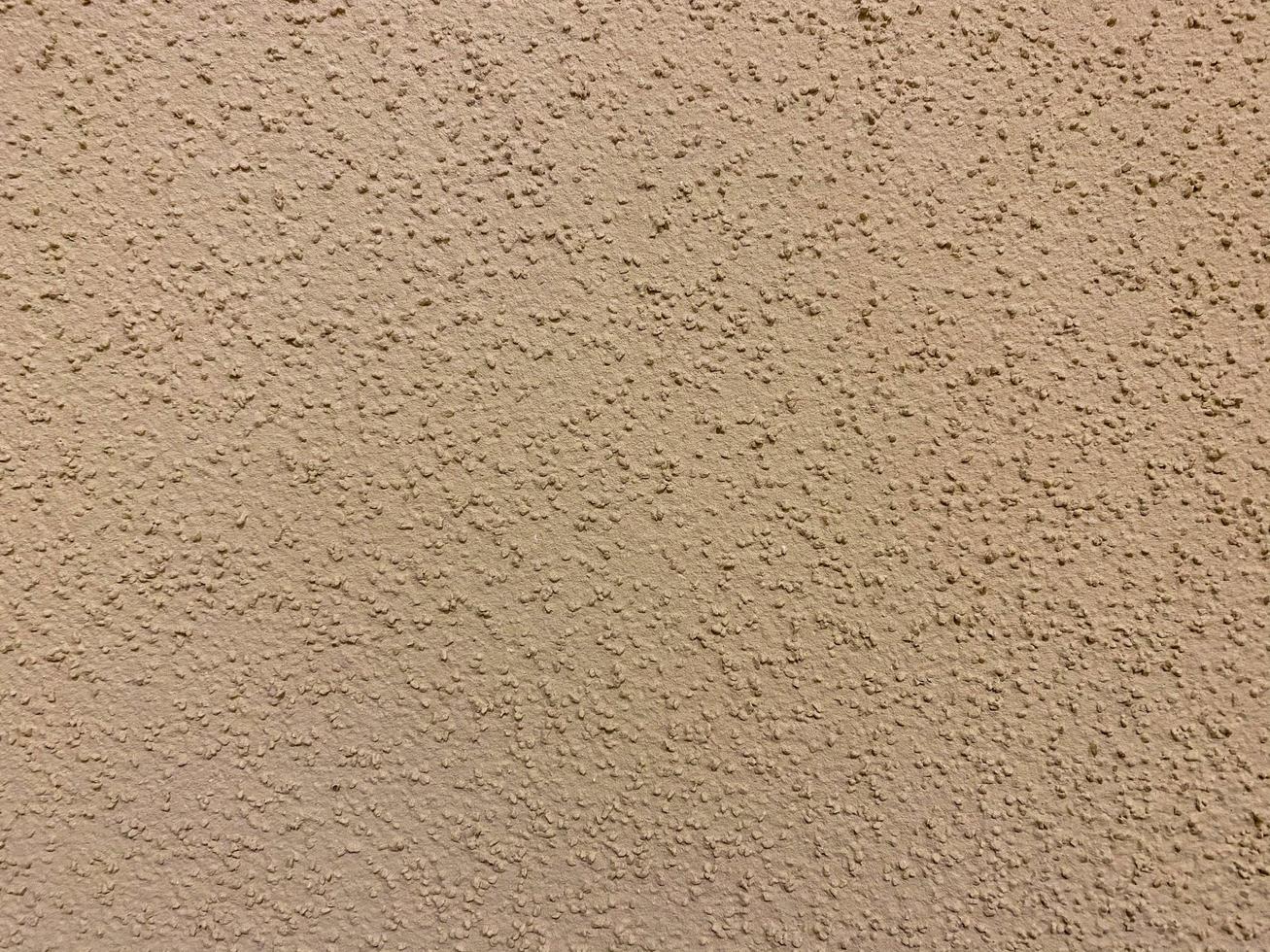 The texture of the beige yellow surface of the plaster-plastered wall with bark beetle type plaster on the wall in the entrance. The background photo