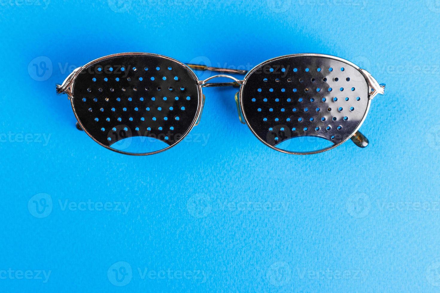 Two different type of glasses on blue background. Medical concept. Top view. Pinhole black eyeglasses help relaxing weary eyes Isolated on white background. Classic Fashion optical eyeglasses photo