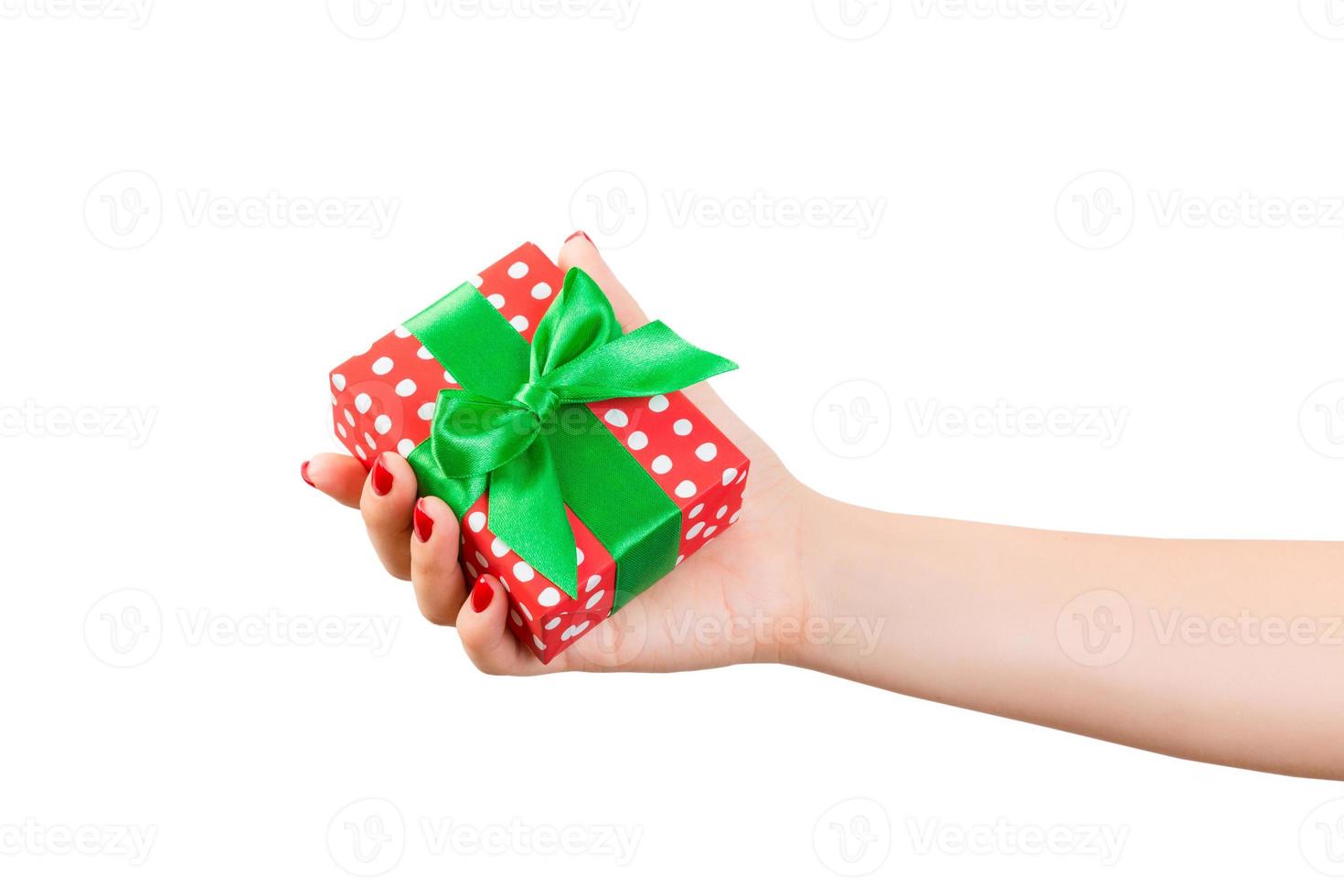 Woman hands give wrapped Christmas or other holiday handmade present in red paper with Green ribbon. Isolated on white background, top view. thanksgiving Gift box concept photo