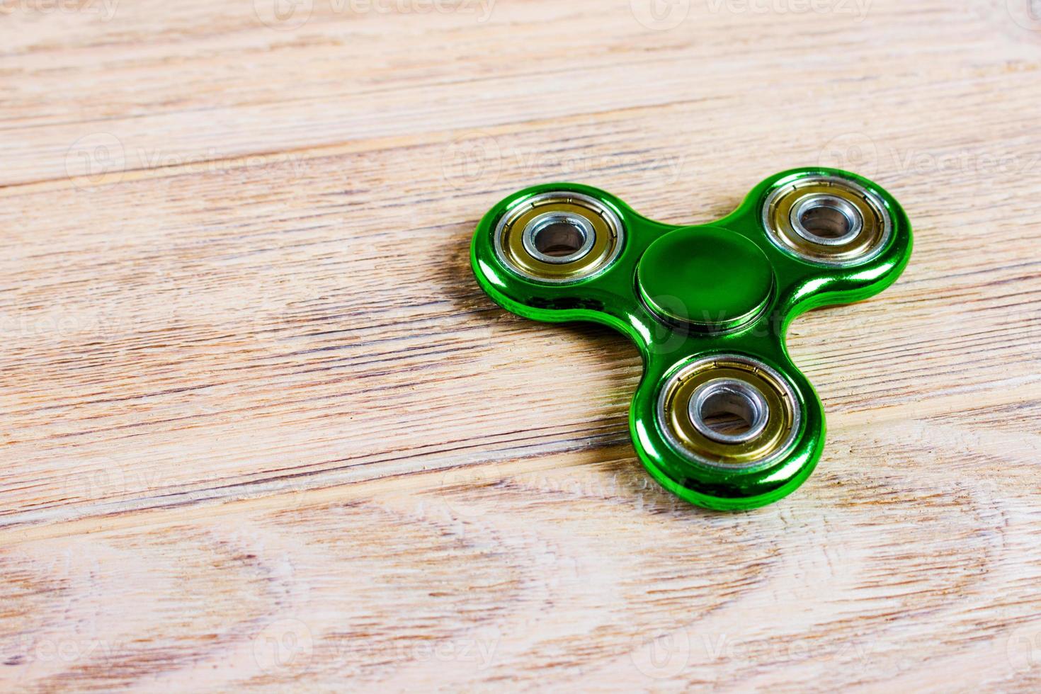 Green fidget spinner stress relieving toy on wood background photo