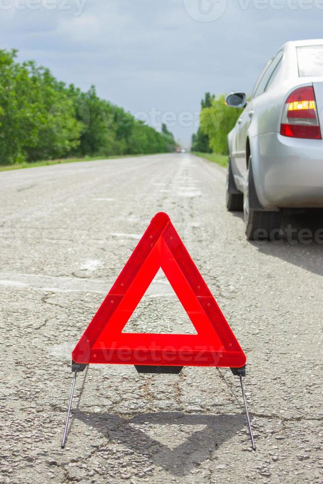 triángulo rojo de un coche en la carretera. avería del coche con mal tiempo foto