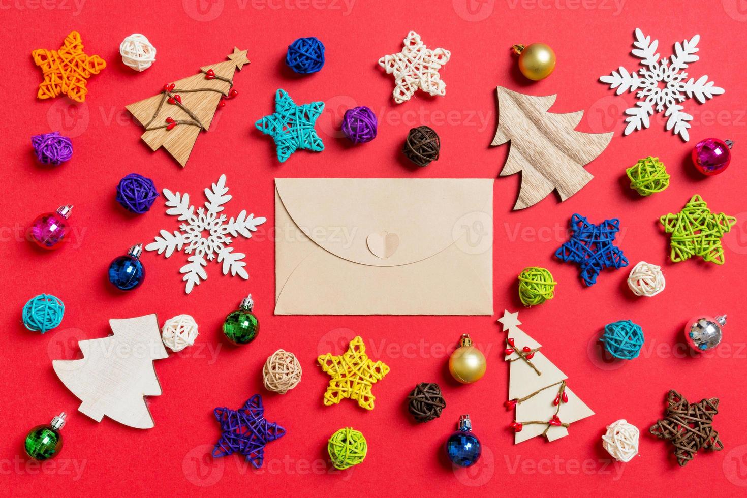 Top view of craft envelope on red background made of holiday decorations and toys. Christmas ornament concept photo