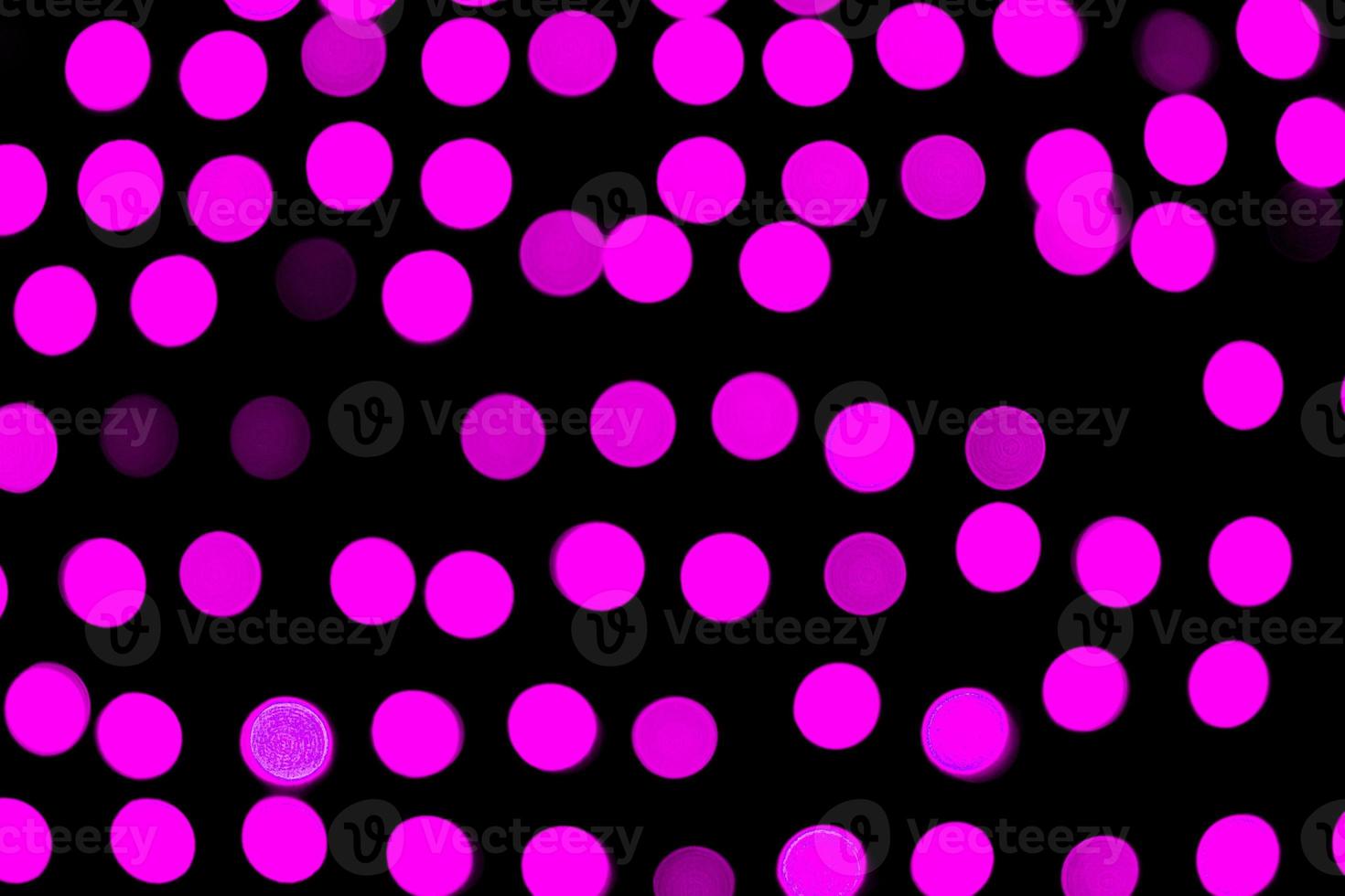Unfocused abstract violet bokeh on black background. defocused and blurred many round light photo
