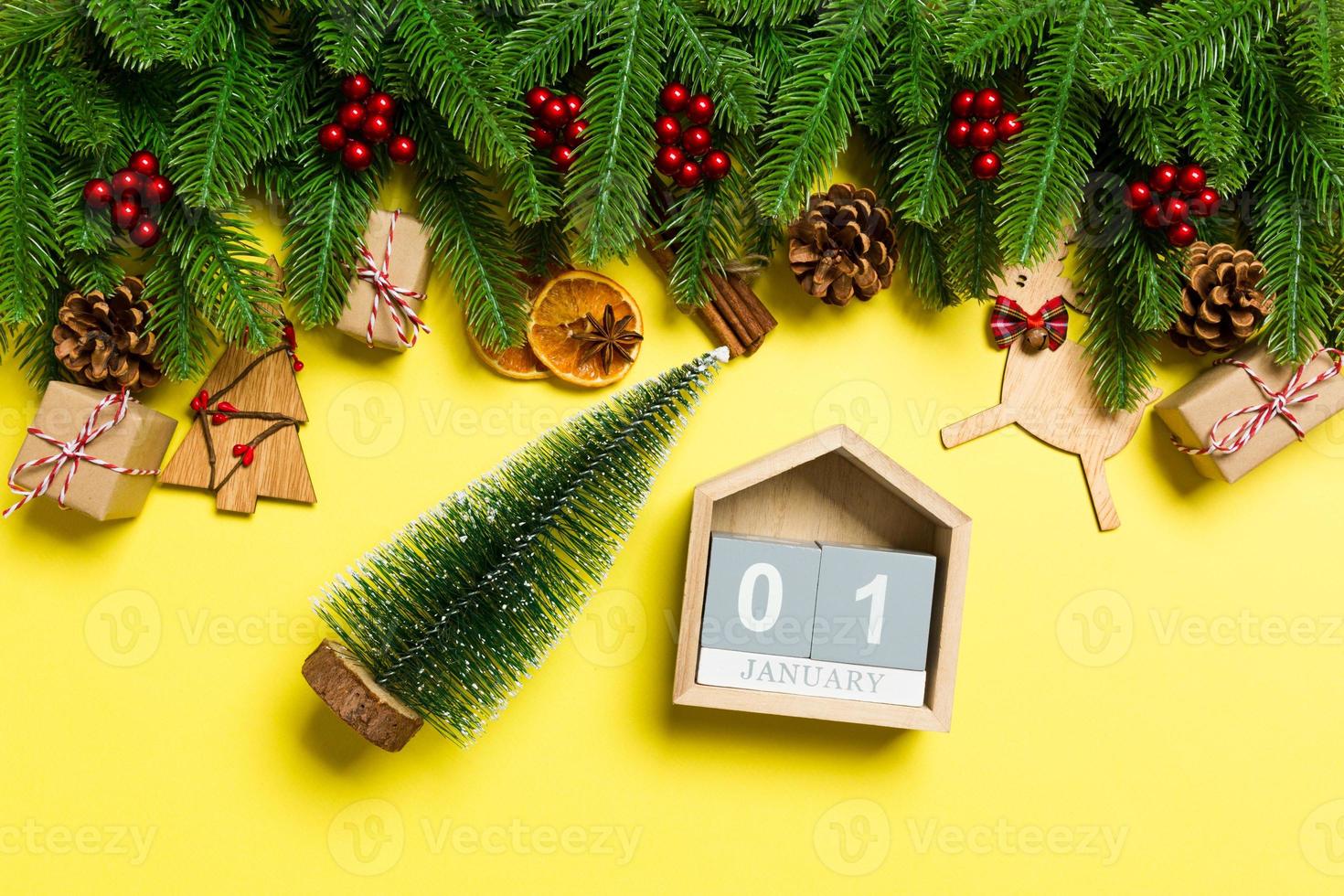 Top view of female hands holding calendar on yellow background. The first of January. Holiday decorations. New Year concept photo