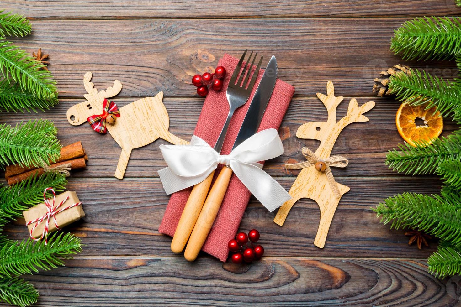 Top view of utensils on festive napkin on wooden background. Christmas decorations with dried fruits and cinnamon. Close up of New year dinner concept photo