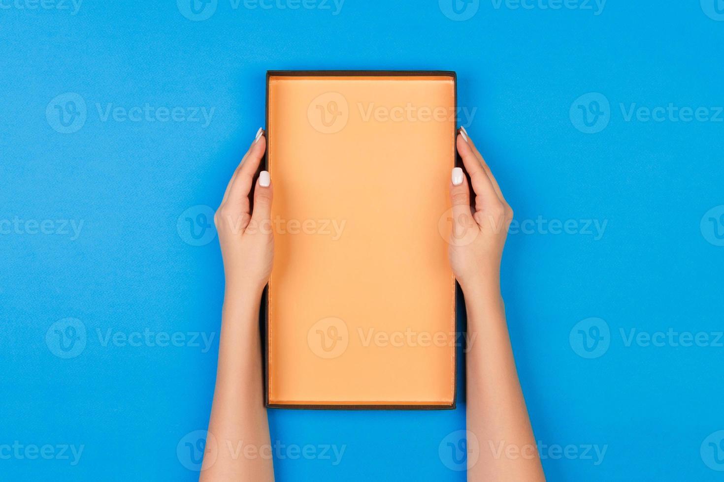 Woman hands holding open box on blue background photo