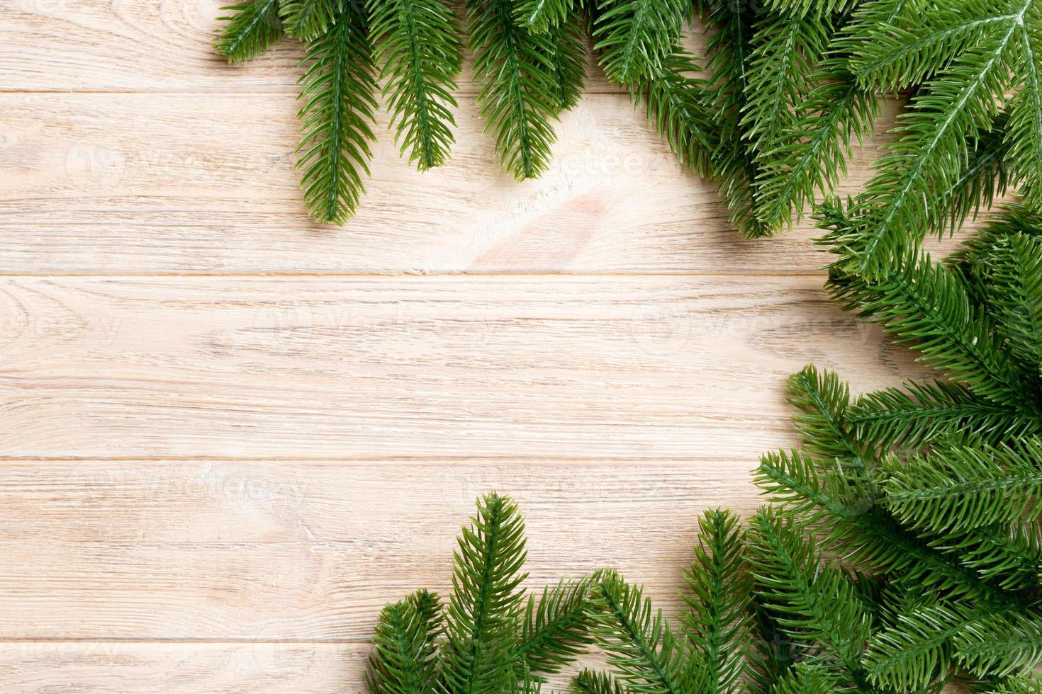 Top view of frame made of fir tree branches on wooden background. Christmas concept with empty space for your design photo