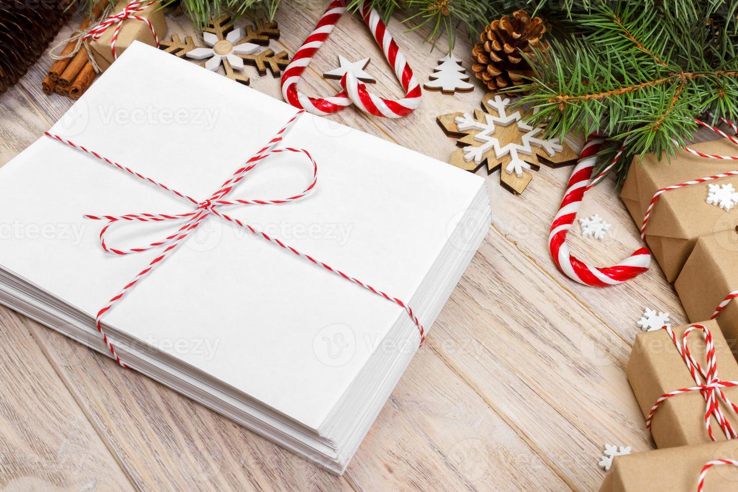 Envelope with blank sheet of paper on Christmas background - fir branch, pine cones, red ribbon, star and heart of sweets. Space for your text photo