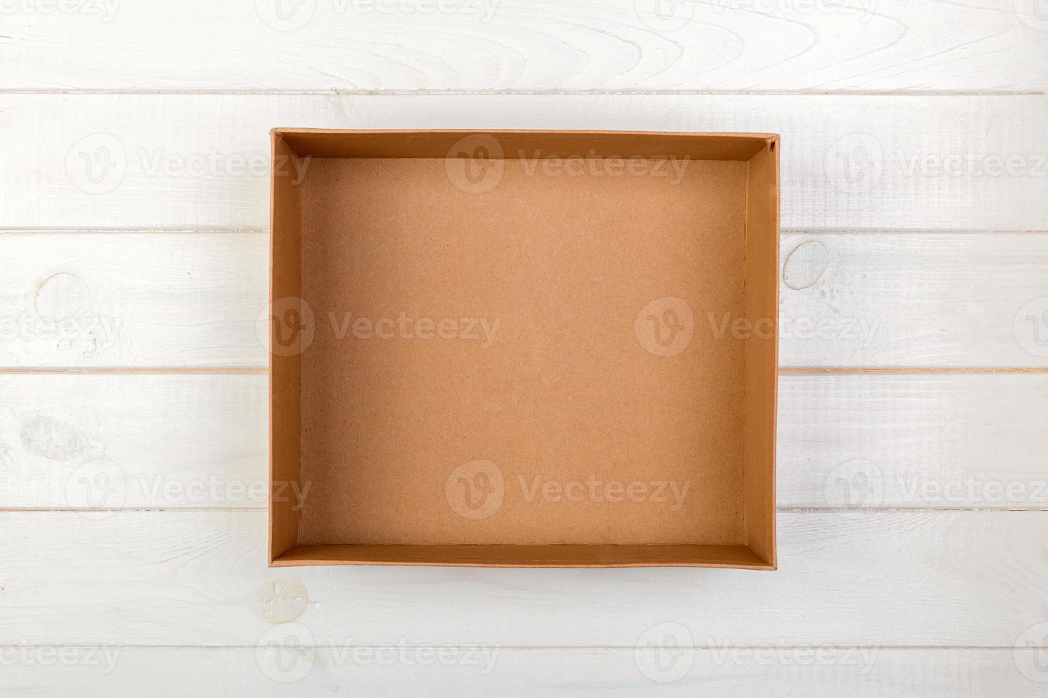 Opened brown blank cardboard box on wooden background, top view photo