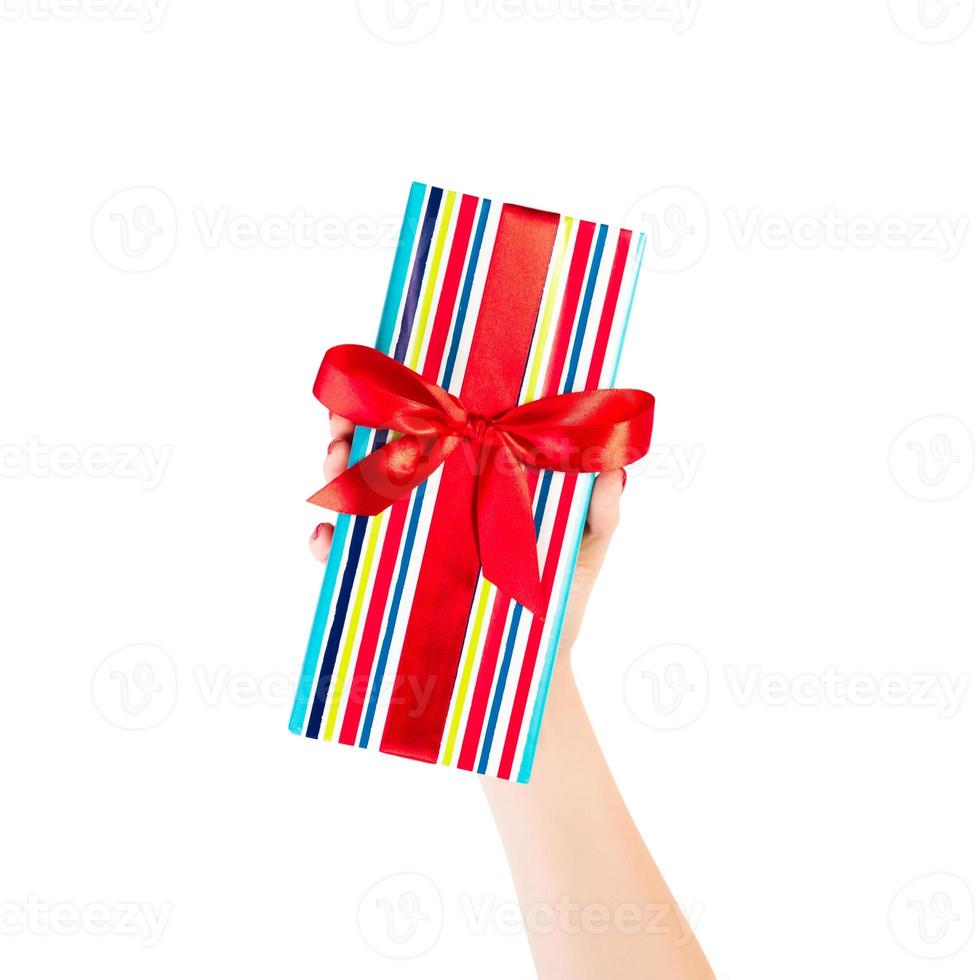 Woman hands give wrapped Christmas or other holiday handmade present in colored paper with red ribbon. Isolated on white background, top view. thanksgiving Gift box concept photo