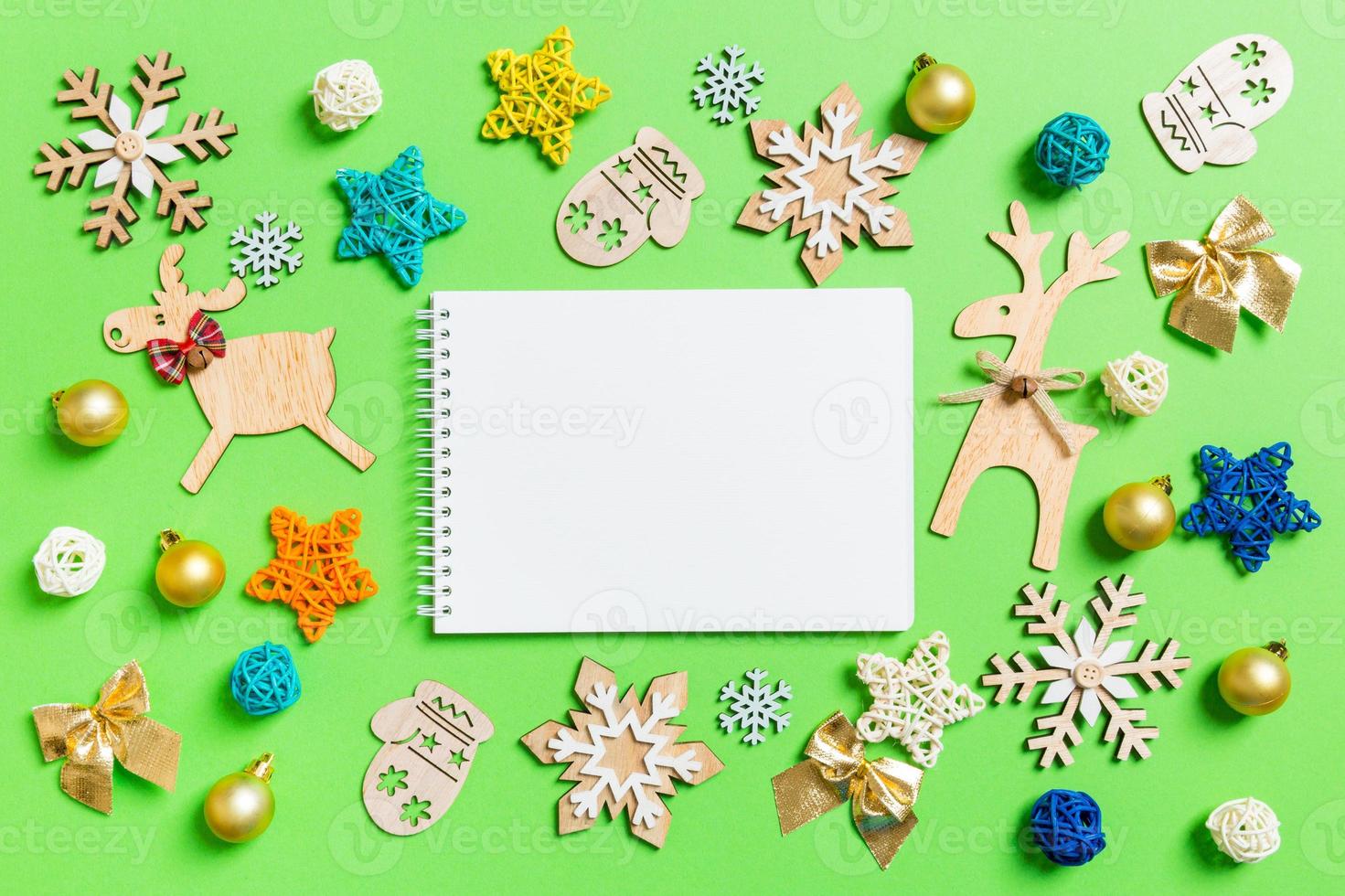 Top view of notebook on green background with New Year toys and decorations. Christmas time concept photo