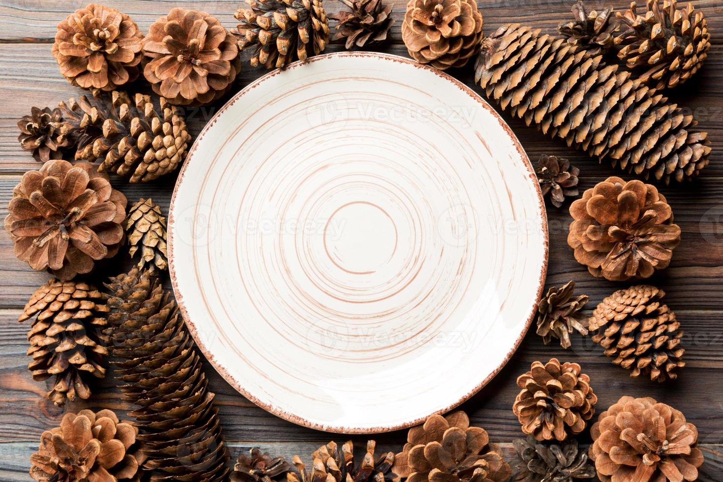 Top view of festive plate with pine cones on wooden background. New Year dinner concept photo