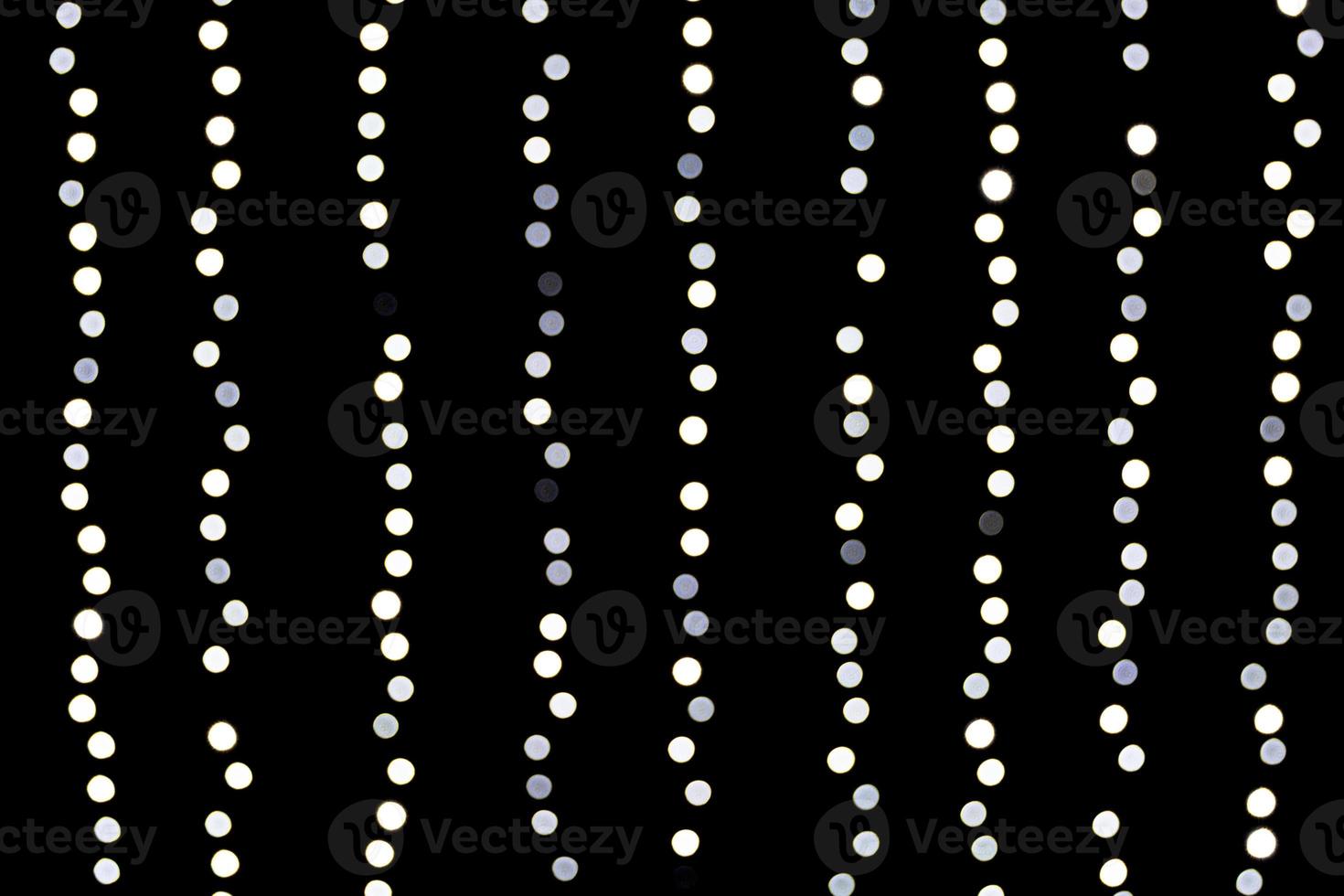 Bokeh white lights on black background. Abstract defocused many round light photo