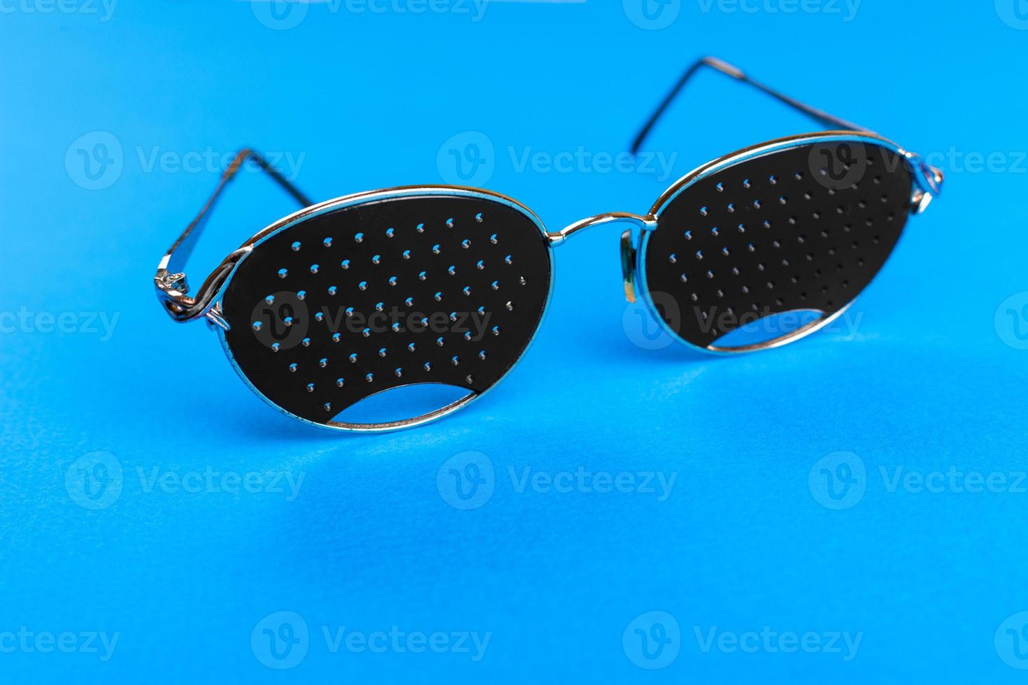 Glasses trainers. Black pinhole glasses on blue background. Medical concept. Top view photo