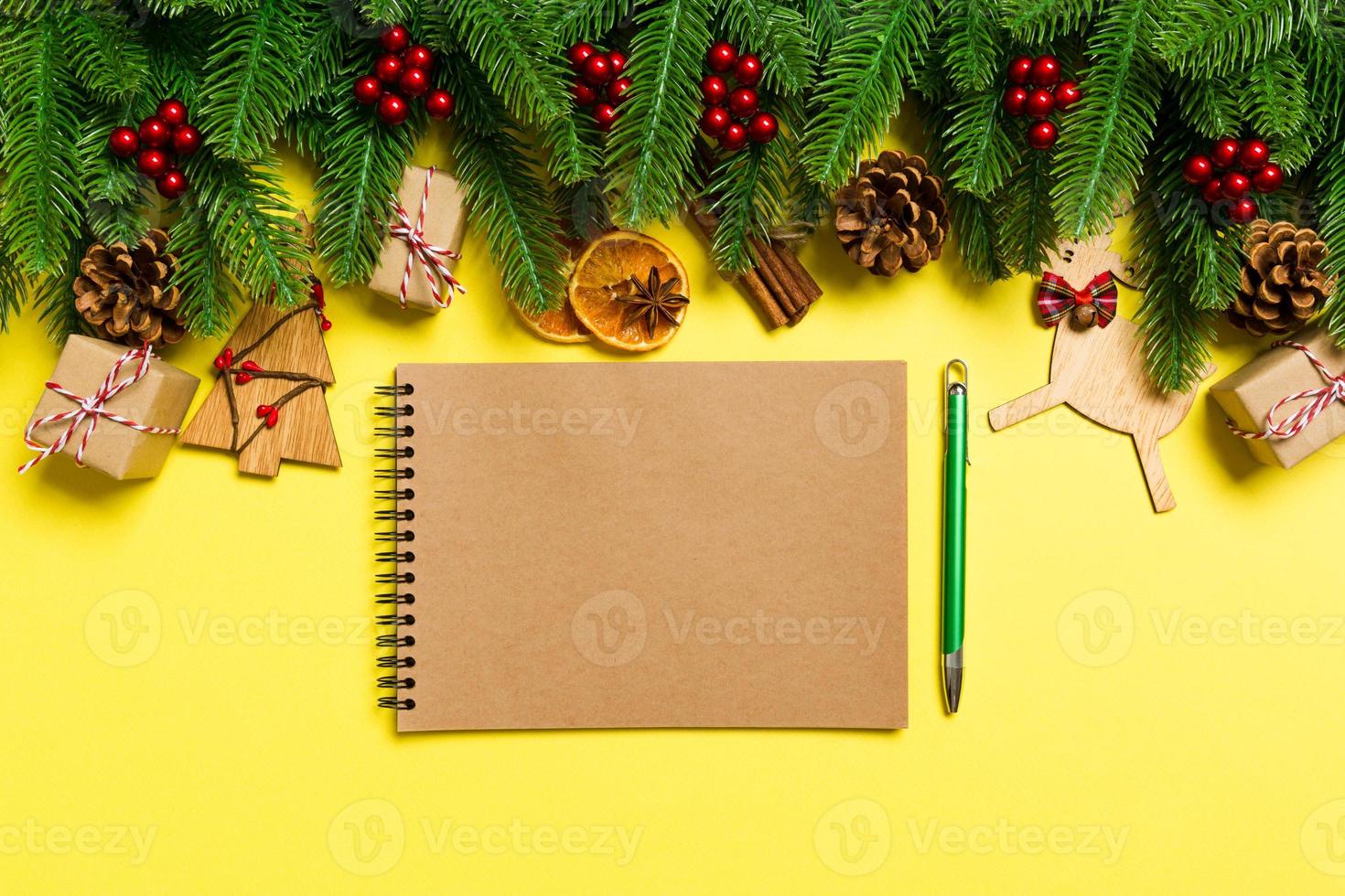Top view of notebook on yellow background made of Christmas decorations. New Year time concept photo