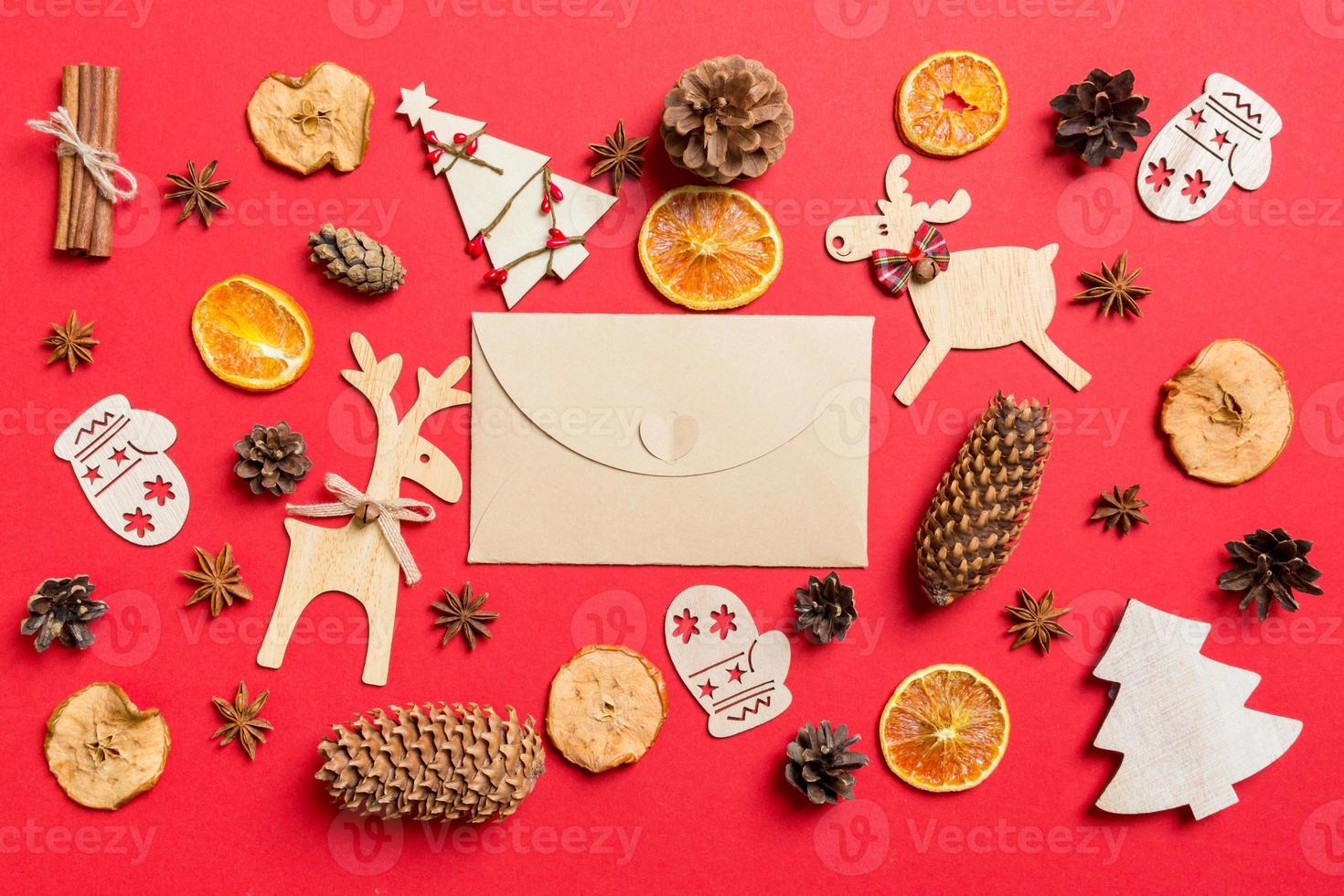 Top view of craft envelope, red background decorated with festive toys and Christmas symbols reindeers and New Year trees. Holiday concept photo