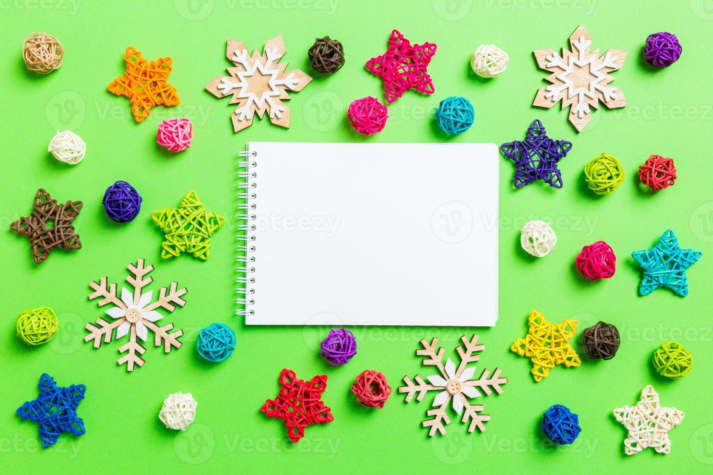 vista superior del cuaderno. decoraciones de año nuevo sobre fondo verde. estrellas festivas y bolas. concepto de feliz navidad foto