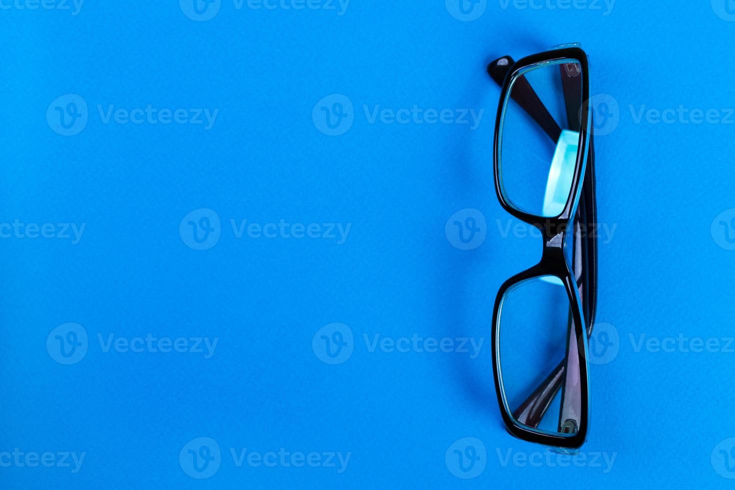 Modern fashionable and office spectacles on blue background, Perfect reflection, eye glasses on table for copy space photo