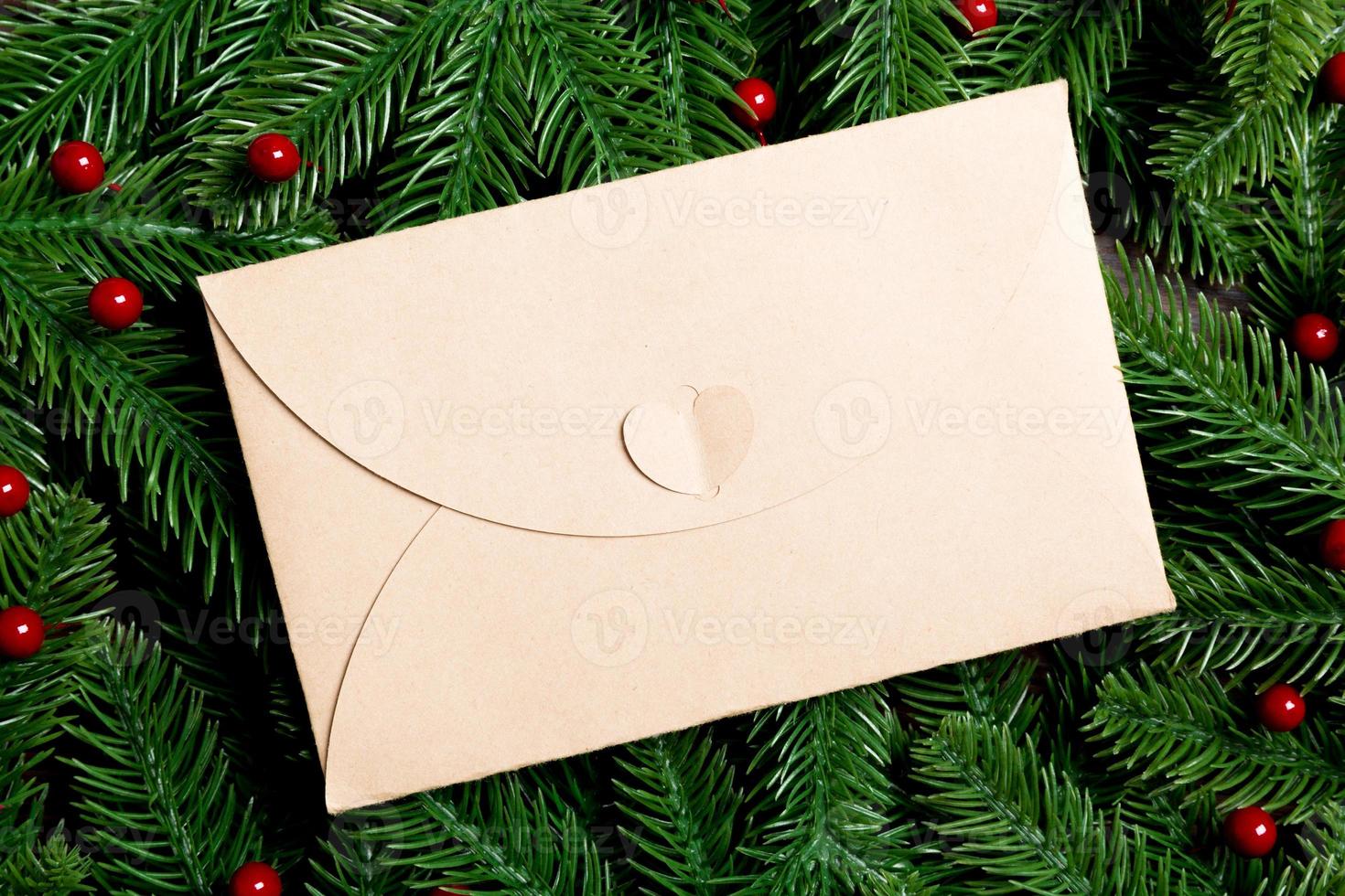 Top view of envelope decorated with a frame made of fir tree on wooden background. New Year time concept photo