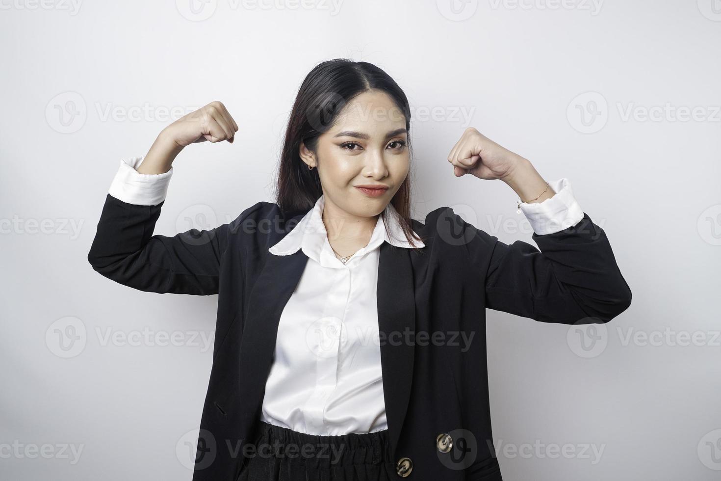 Excited Asian business woman wearing a black suit showing strong gesture by lifting her arms and muscles smiling proudly photo