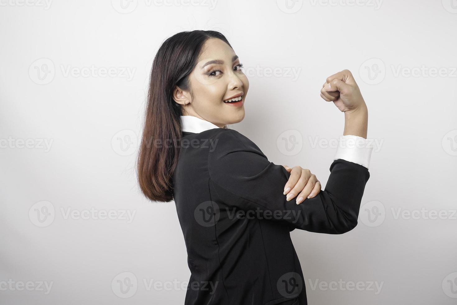 mujer de negocios asiática emocionada con un traje negro que muestra un gesto fuerte levantando los brazos y los músculos sonriendo con orgullo foto