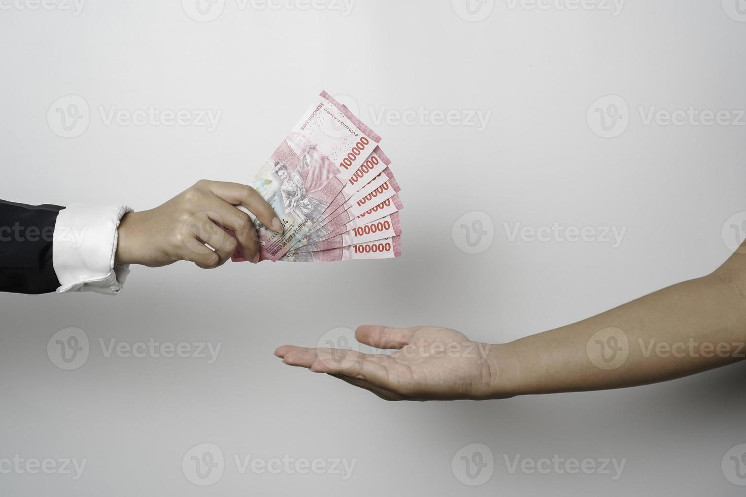 A portrait of businessman giving money in Indonesian Rupiah for business deal or payment or charity photo