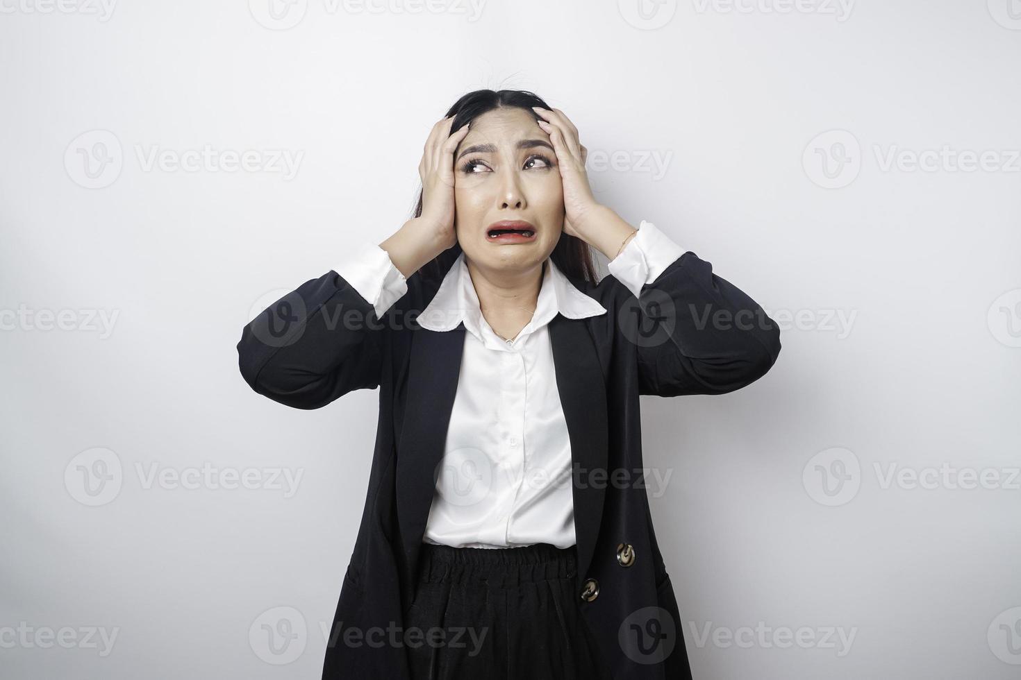 A portrait of an Asian business woman wearing a black suit isolated by white background looks depressed photo