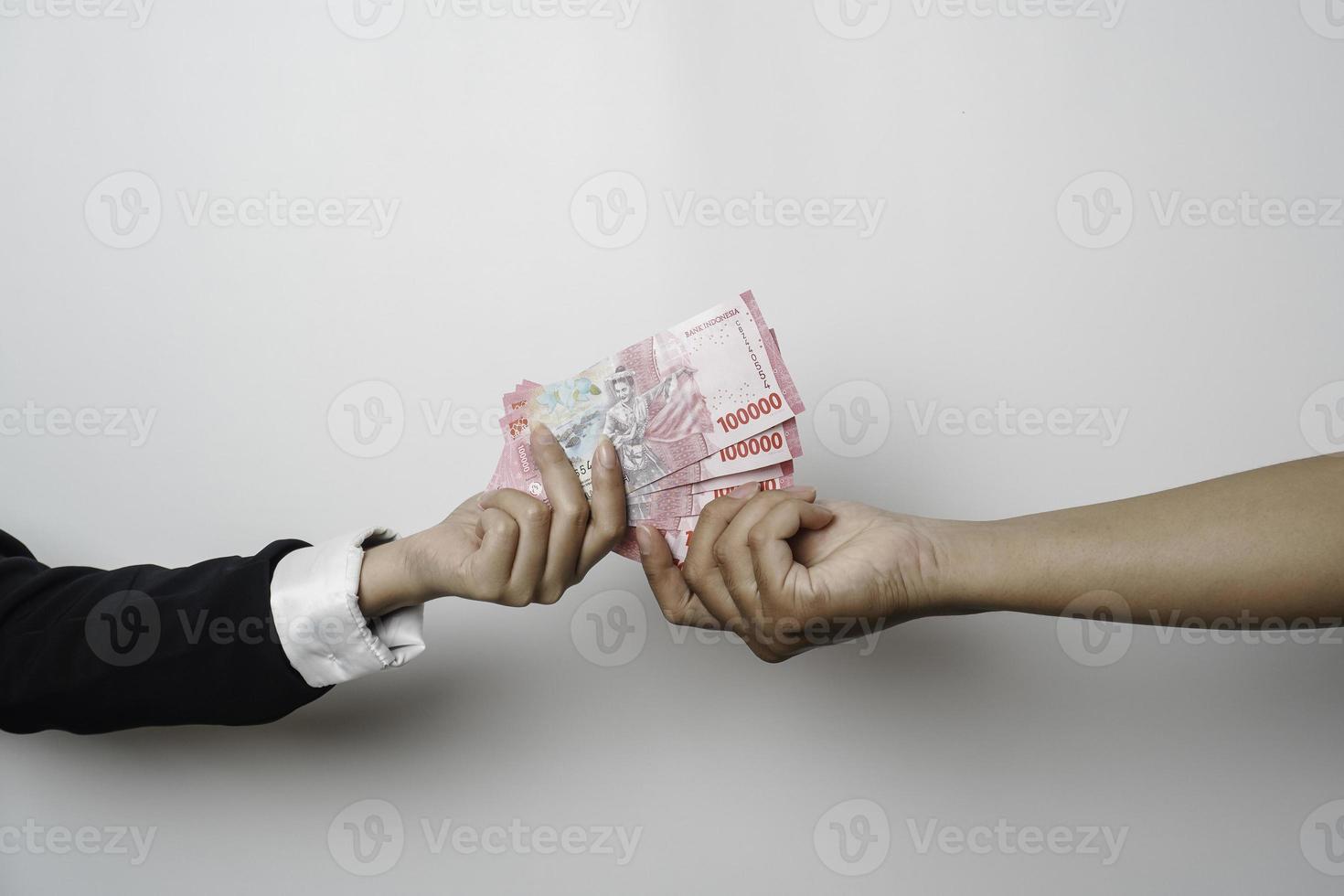 A portrait of businessman giving money in Indonesian Rupiah for business deal or payment or charity photo
