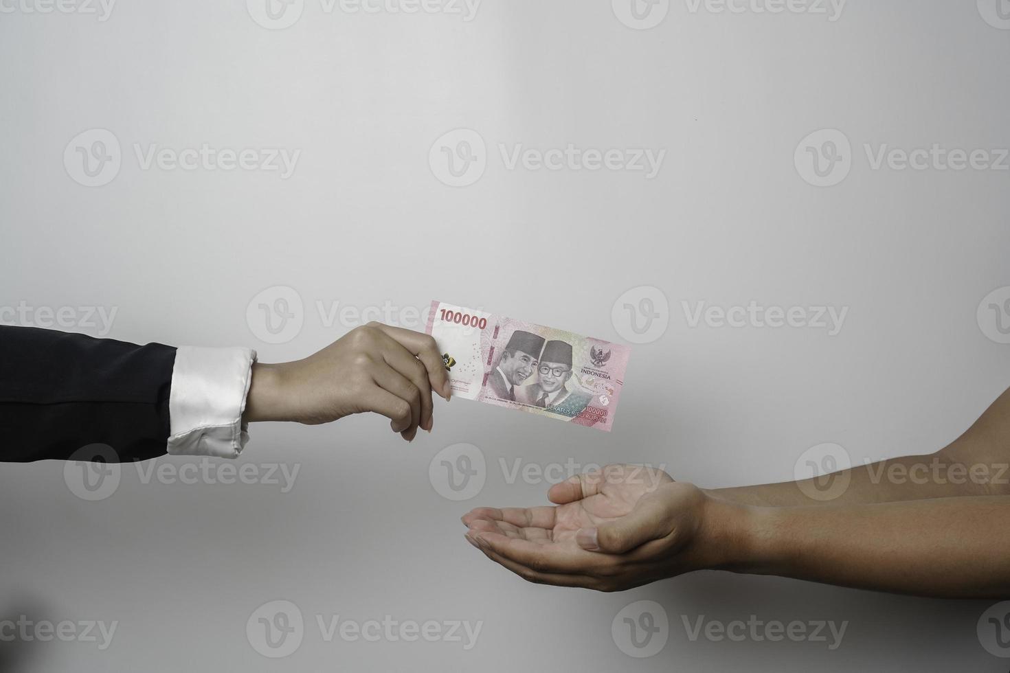 A portrait of businessman giving money in Indonesian Rupiah for business deal or payment or charity photo