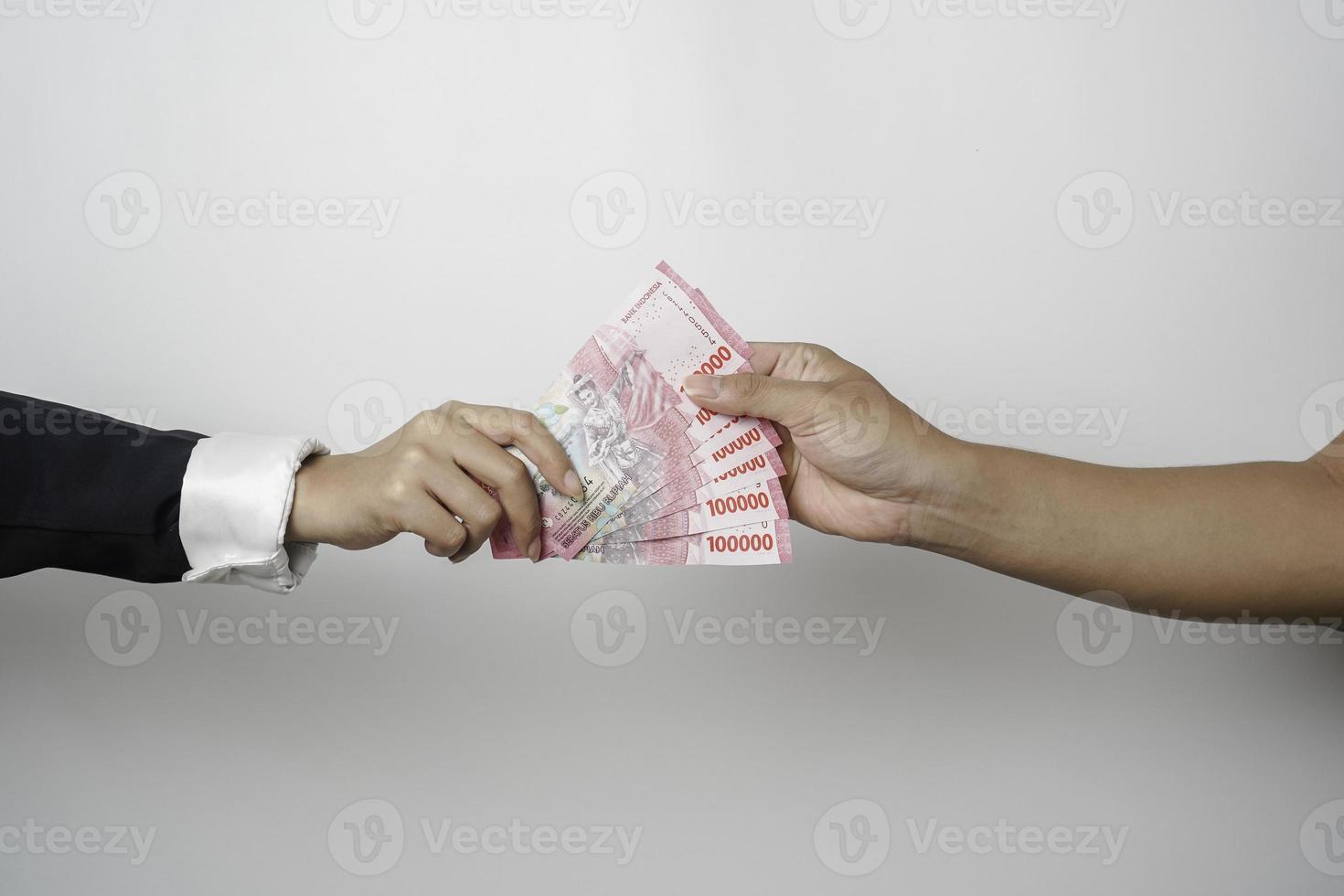 A portrait of businessman giving money in Indonesian Rupiah for business deal or payment or charity photo