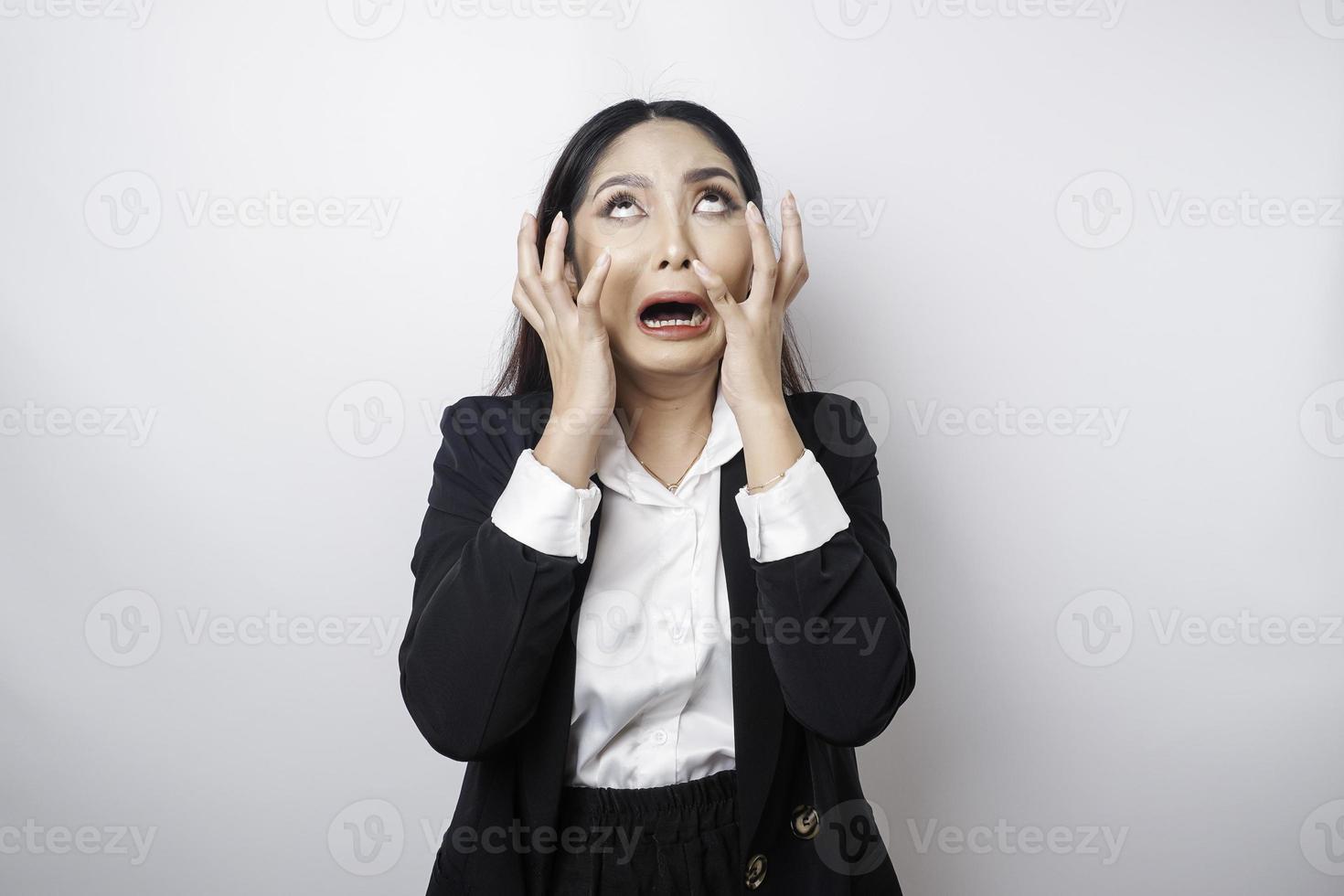 A portrait of an Asian business woman wearing a black suit isolated by white background looks depressed photo