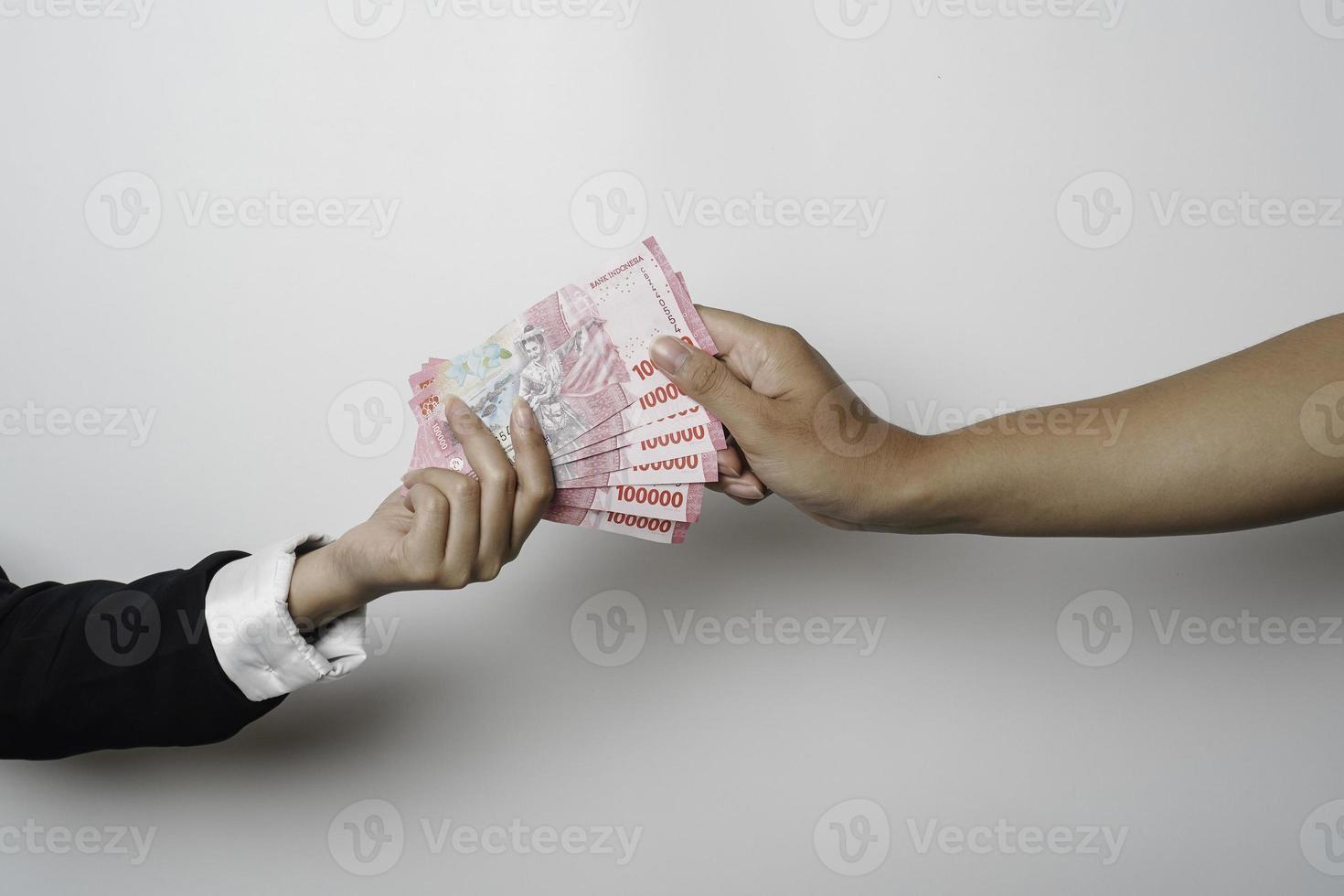 A portrait of businessman giving money in Indonesian Rupiah for business deal or payment or charity photo