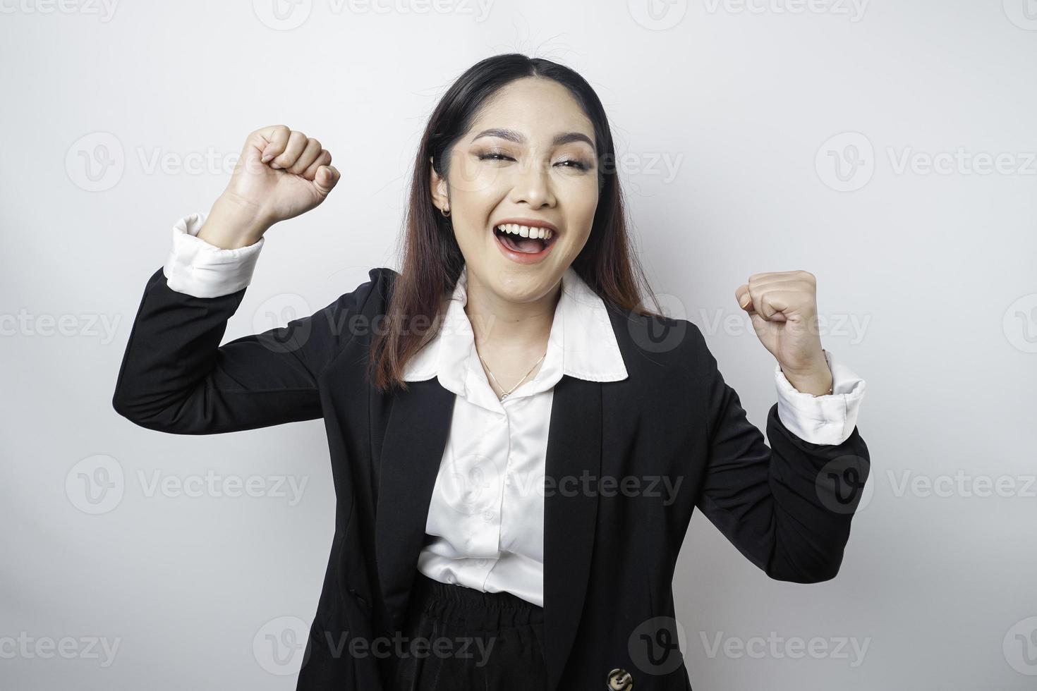 una joven mujer de negocios asiática con una expresión feliz y exitosa con traje negro aislada de fondo blanco foto